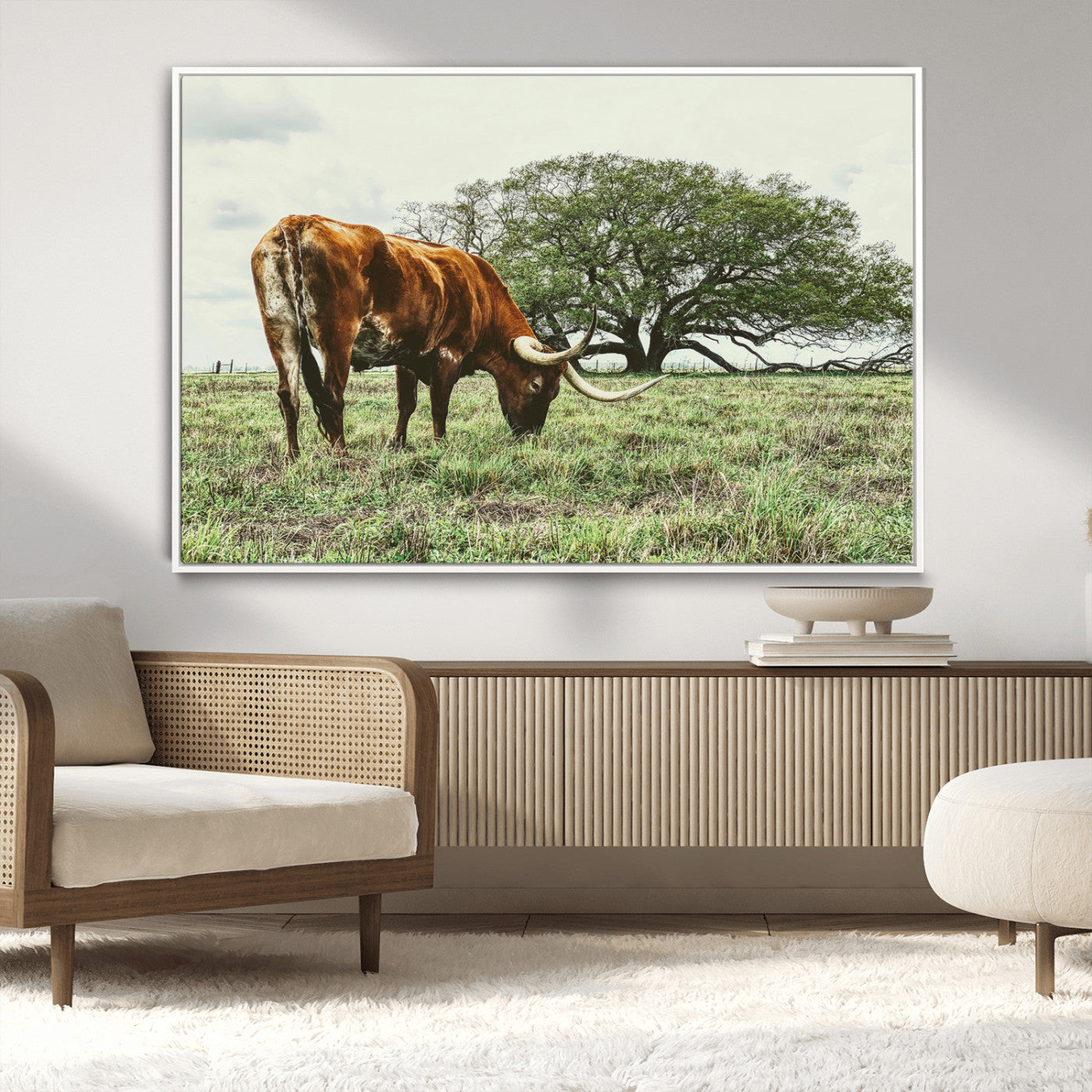 A Texas Longhorn grazing in a green pasture with a large tree in the background, evoking a rustic Western and farmhouse aesthetic.