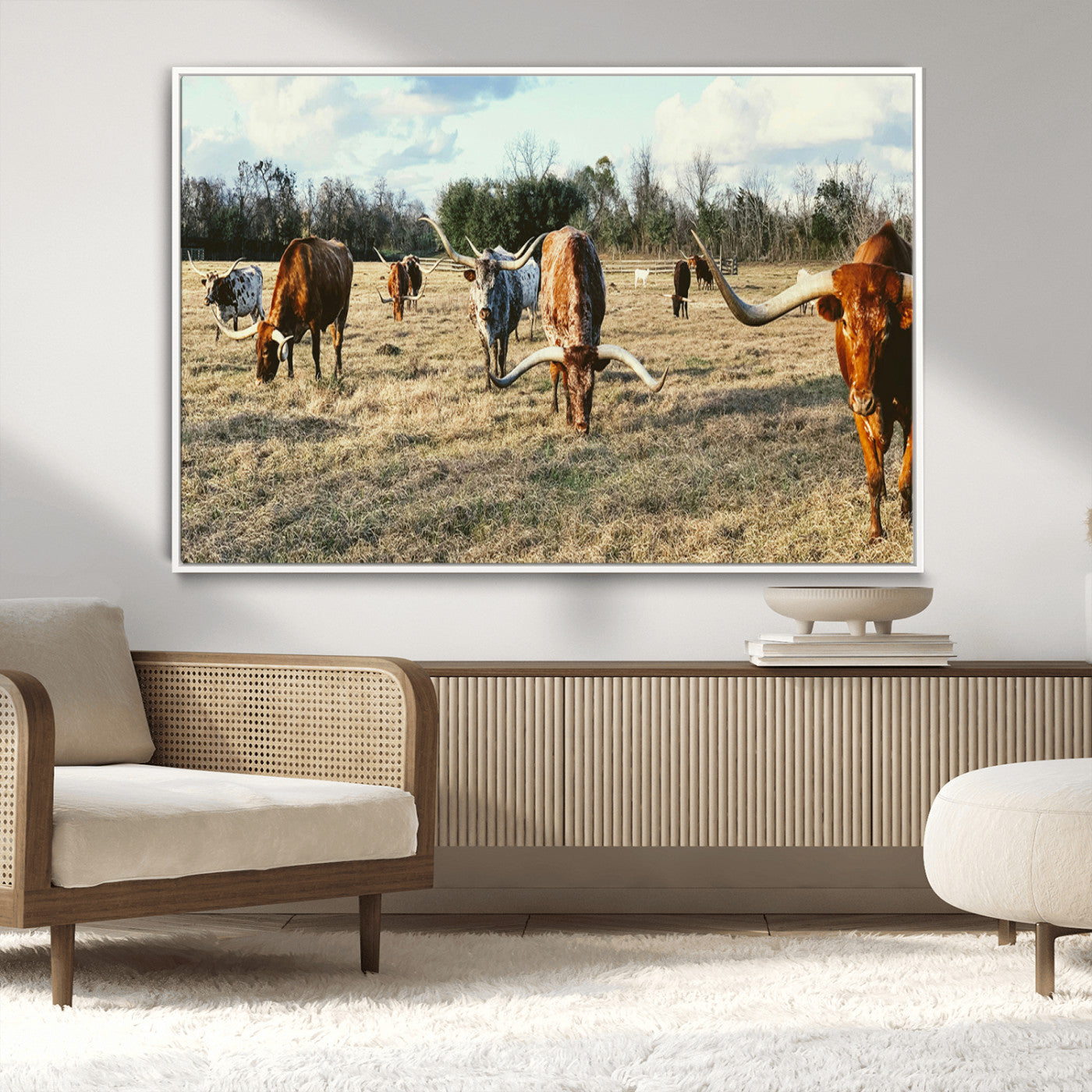A herd of Texas Longhorn cattle grazing in an open field under a partly cloudy sky, capturing a rustic and Western ranch aesthetic.