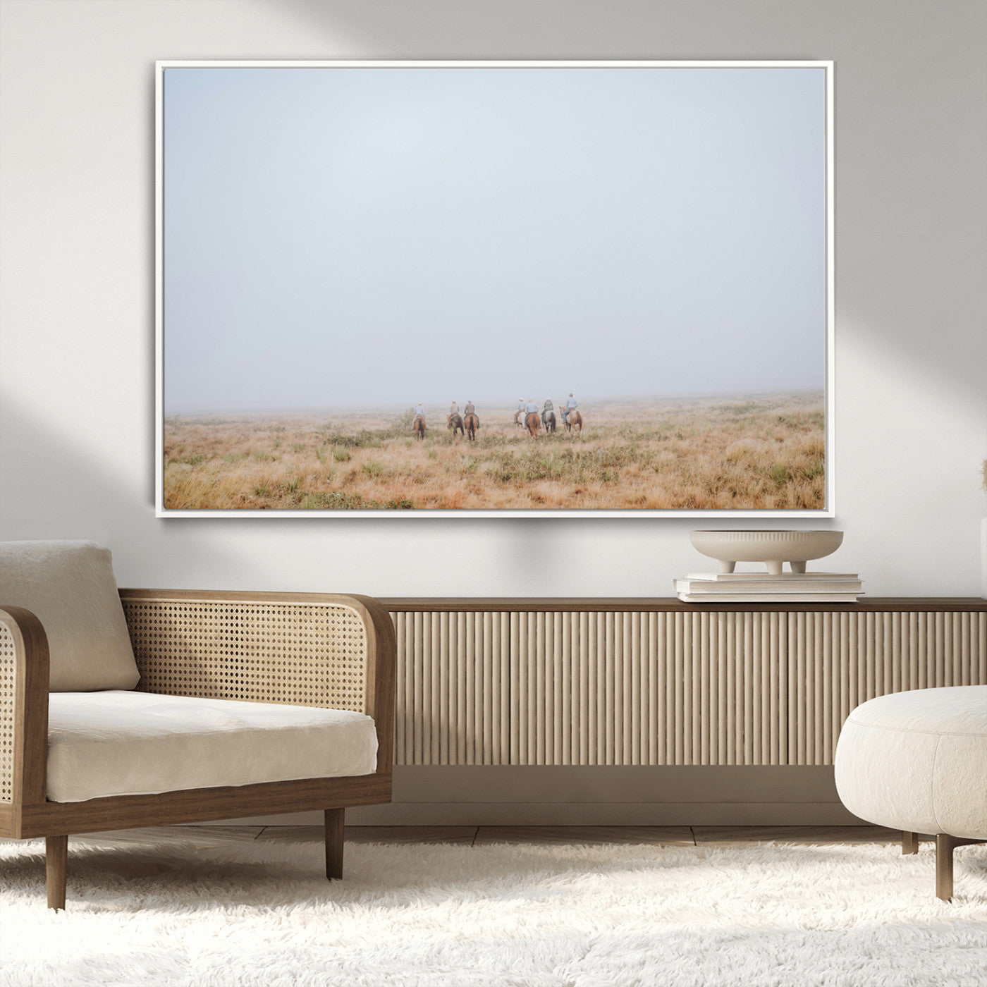 A group of horseback riders moving through a fog-shrouded field, evoking a calm Western scene with golden grasses and soft horizons.