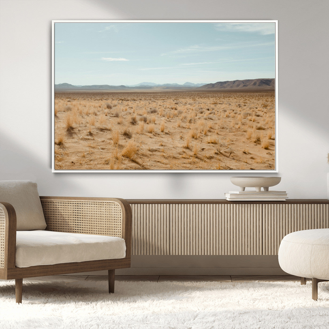 Expansive desert landscape with scattered dry grass and distant mountain range under a pale blue sky – Wall Art Canvas Print.