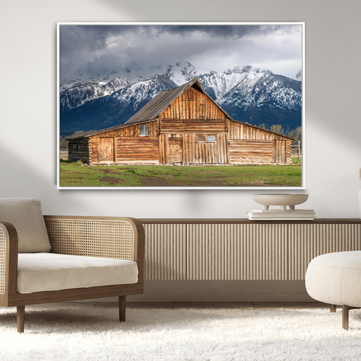 A stunning wall art canvas print featuring a rustic wooden barn set against a backdrop of snow-capped mountains under a dramatic cloudy sky, perfect for adding a touch of rural charm to any space.