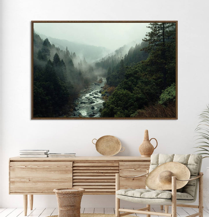 The Misty Forest Wall Art features a serene landscape with a misty river and evergreens, ideal for enhancing the ambiance of any living room or cabin.