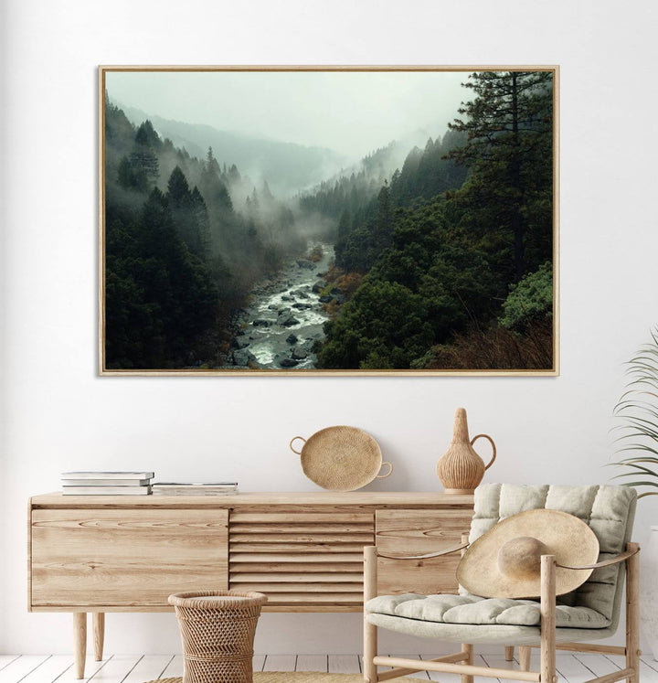 The Misty Forest Wall Art features a serene landscape with a misty river and evergreens, ideal for enhancing the ambiance of any living room or cabin.