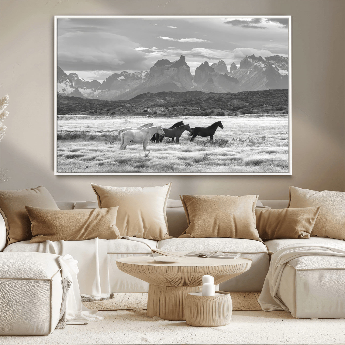 A black and white landscape of wild horses grazing in a vast grassland with towering mountains in the background, creating a moody and rustic western aesthetic.