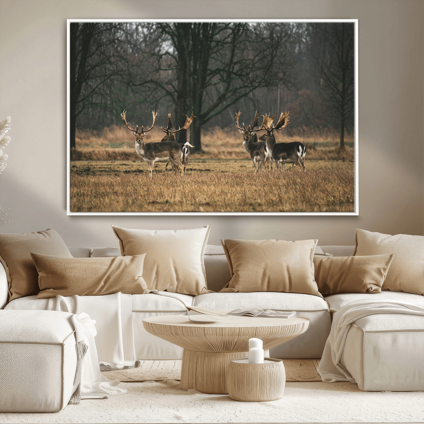 A group of majestic deer standing in a golden field with bare trees in the background, creating a peaceful woodland scene.