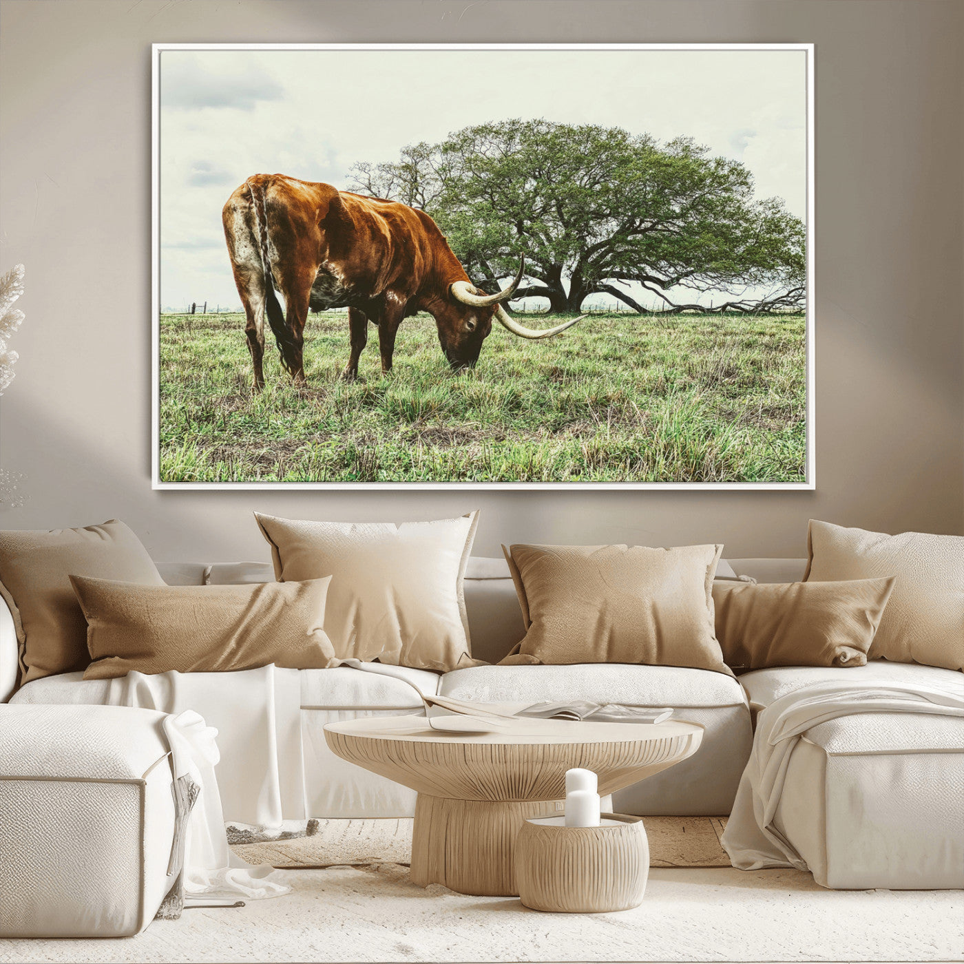 A Texas Longhorn grazing in a green pasture with a large tree in the background, evoking a rustic Western and farmhouse aesthetic.