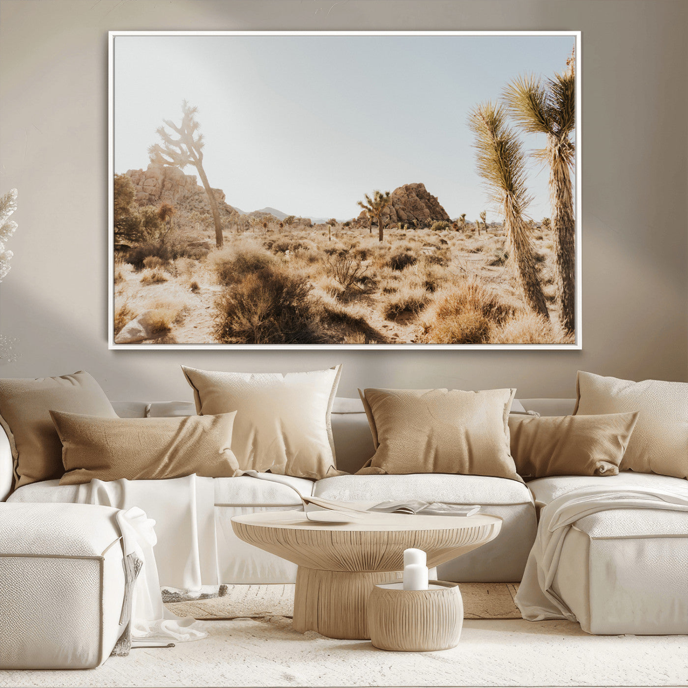 Sunlit desert landscape featuring Joshua trees, rocky formations, and dry bushes under a clear sky.