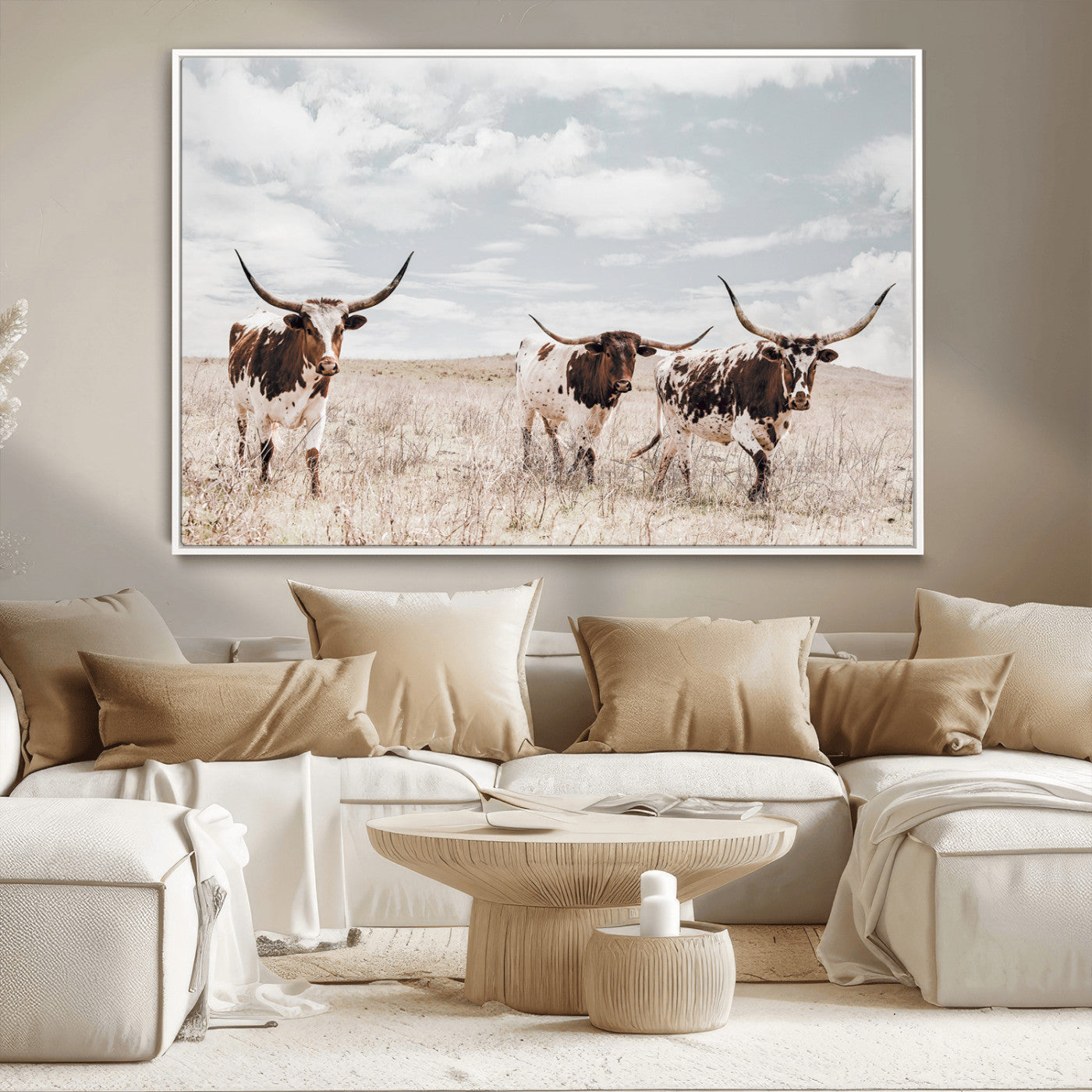 Three Texas Longhorn cattle walking through a dry grassy field under a partly cloudy sky.