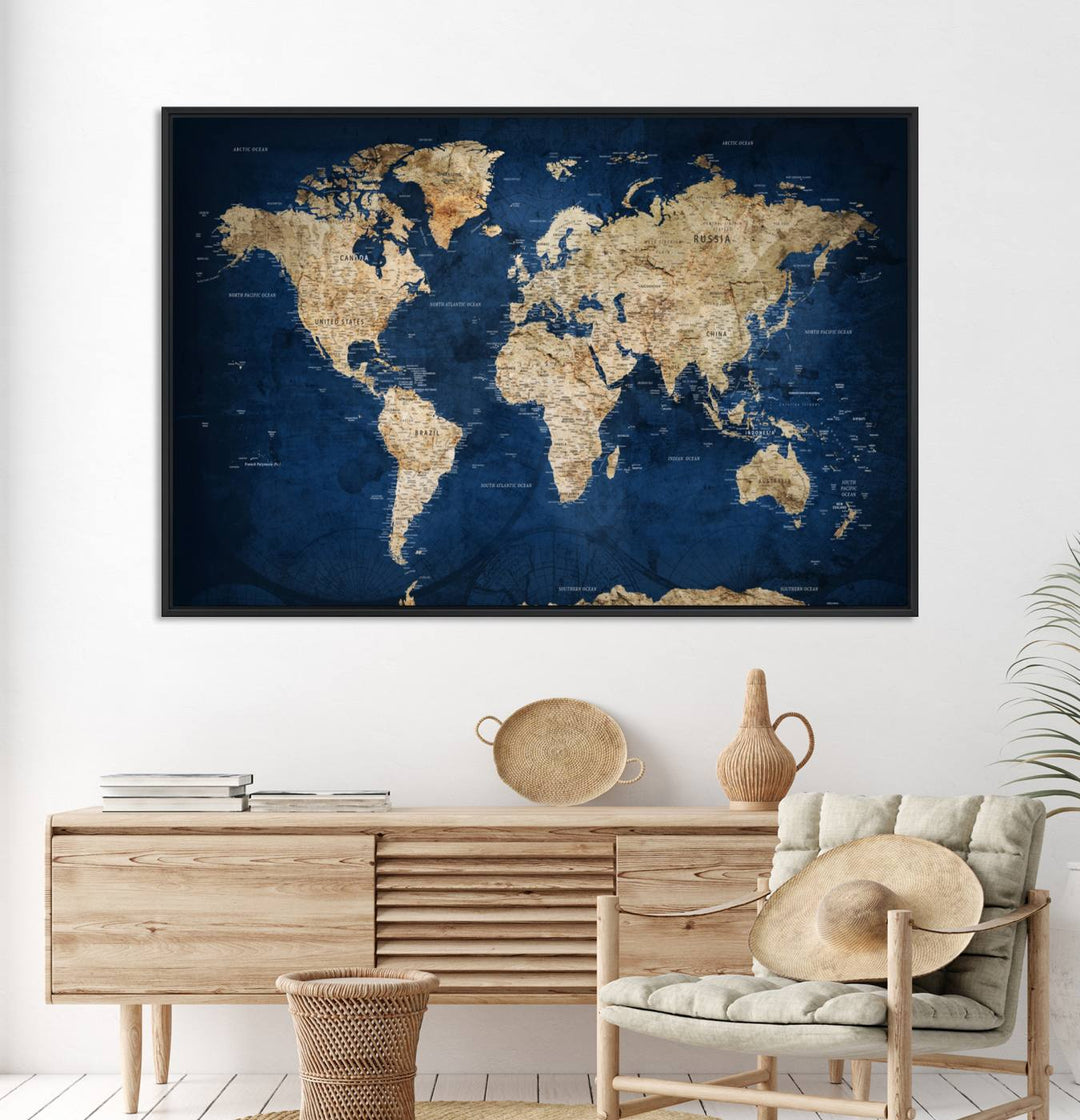 A large framed world map canvas print features beige landmasses set against a grunge-stained deep blue ocean background, creating an intriguing piece of wall art.