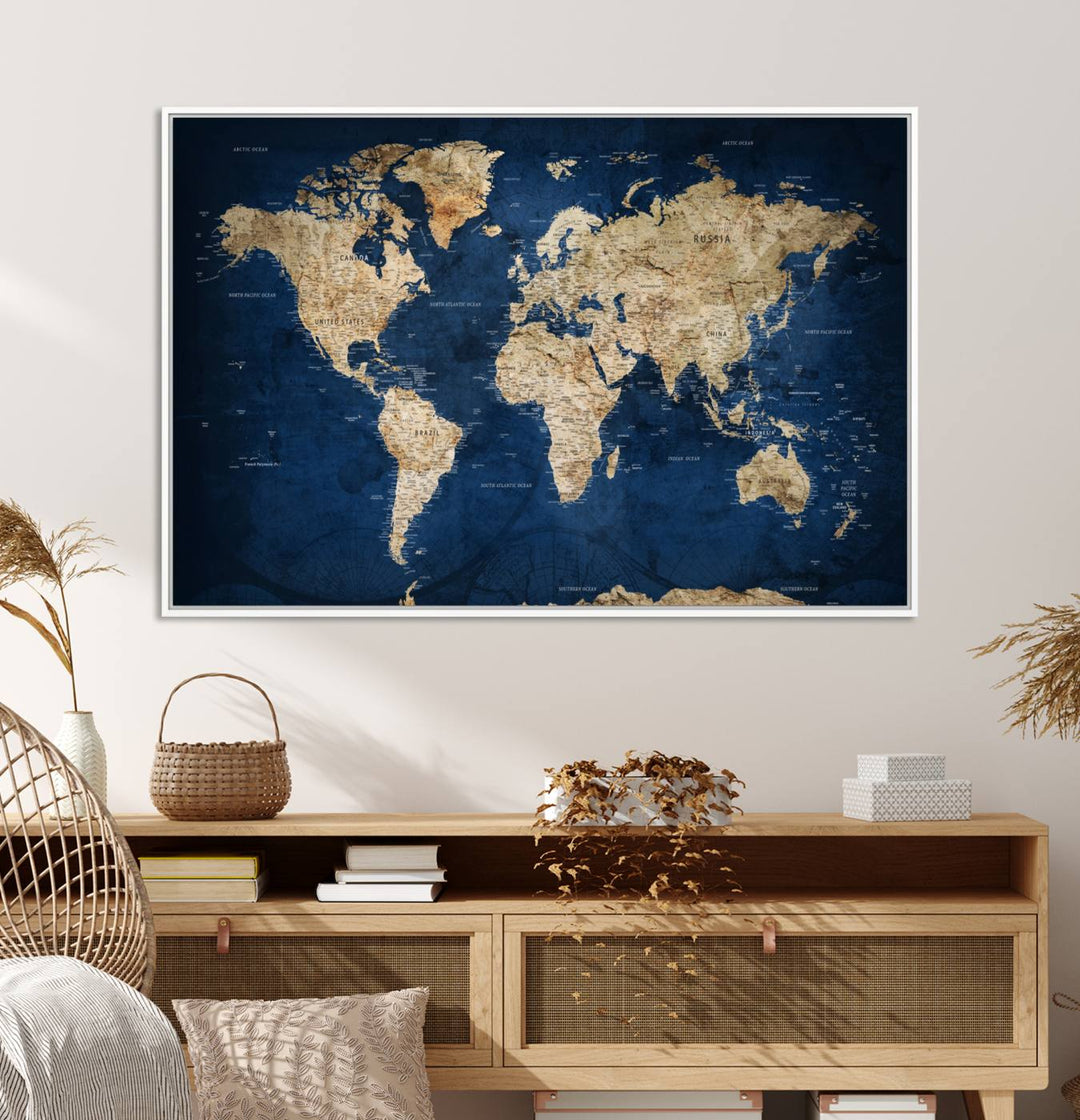 A large framed world map canvas print features beige landmasses set against a grunge-stained deep blue ocean background, creating an intriguing piece of wall art.