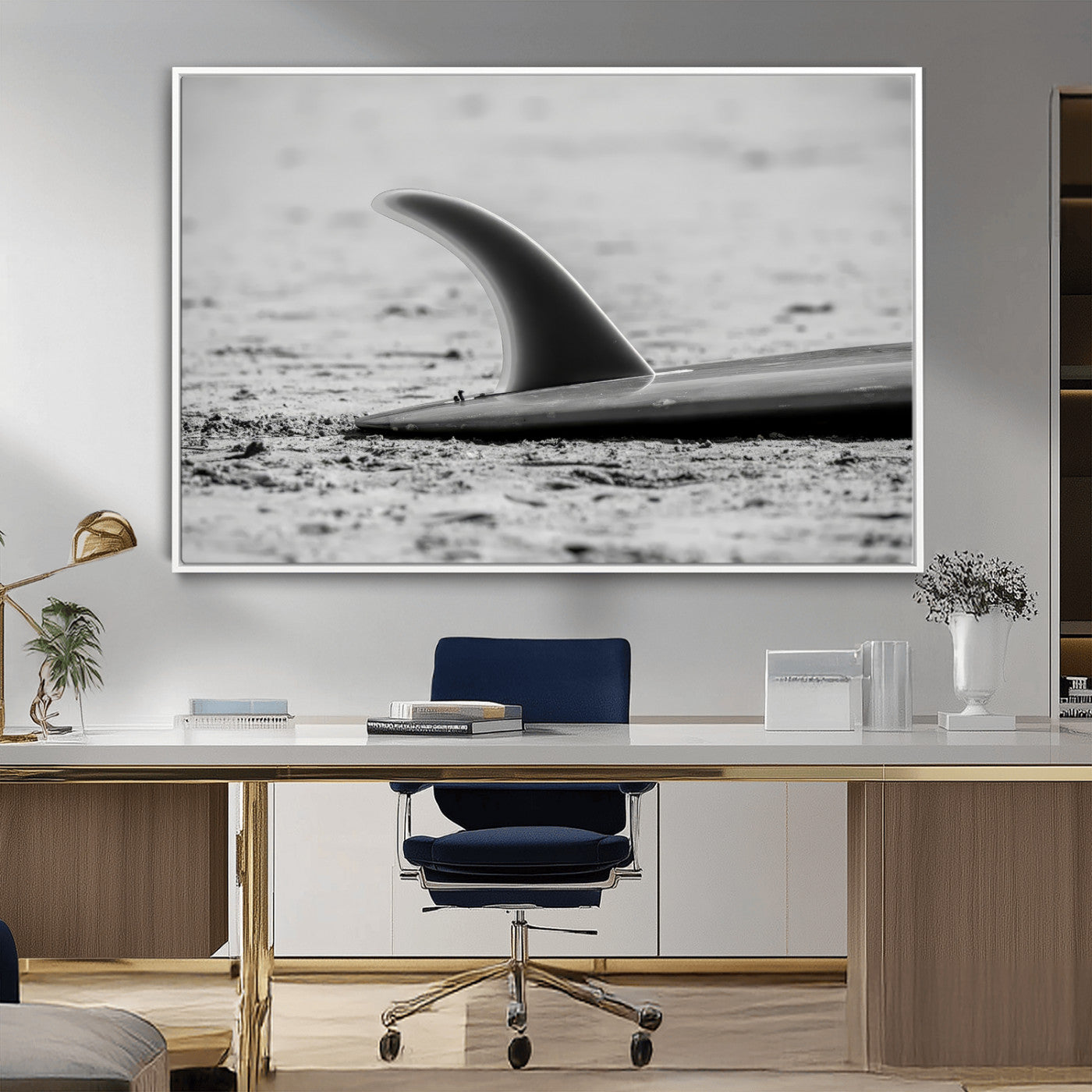 A black and white close-up of a surfboard fin resting on the sandy shore, highlighting minimalist beach aesthetics and classic surf culture.