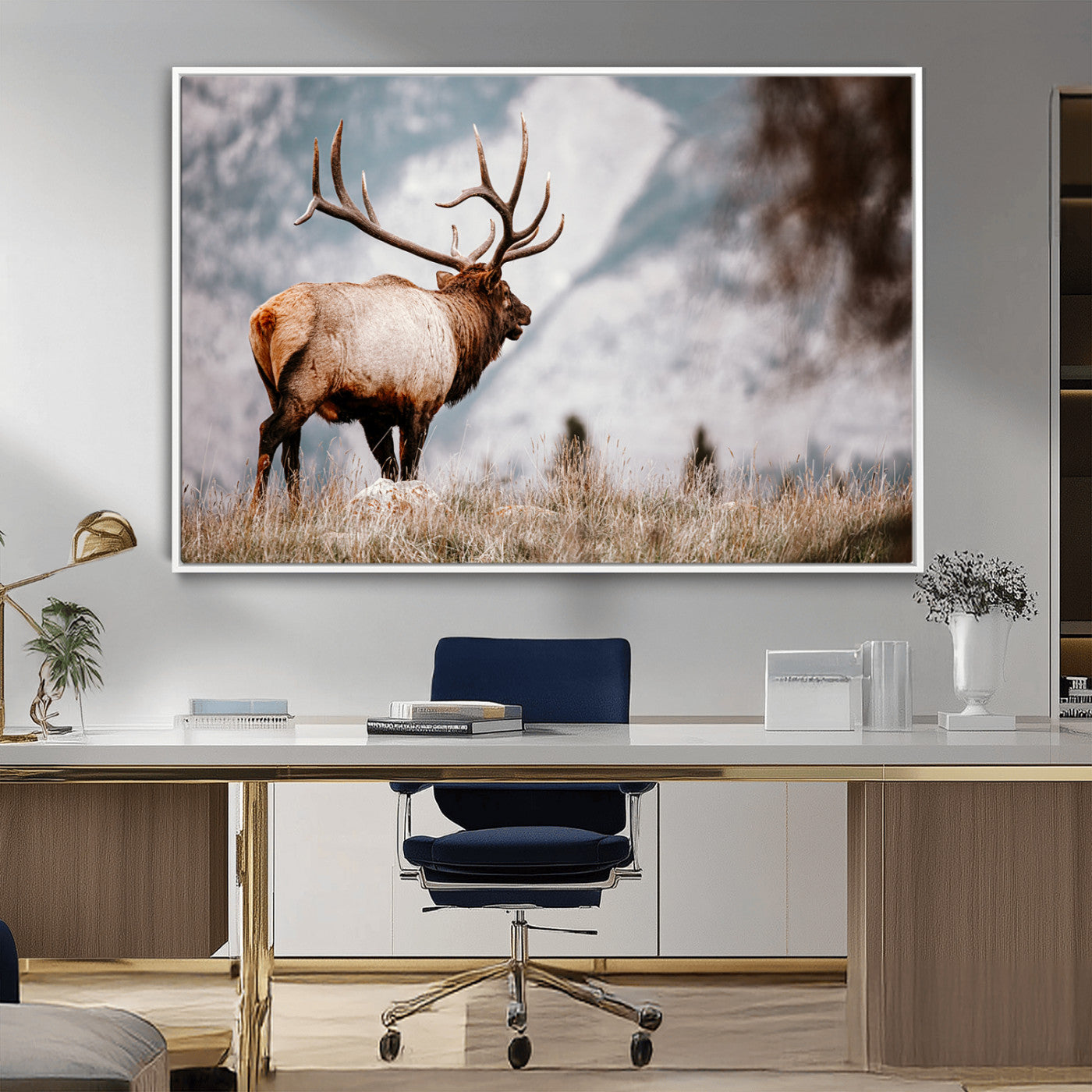 Majestic elk with large antlers standing in grass with snowy mountains in background, perfect for rustic cabin or lodge style decor.