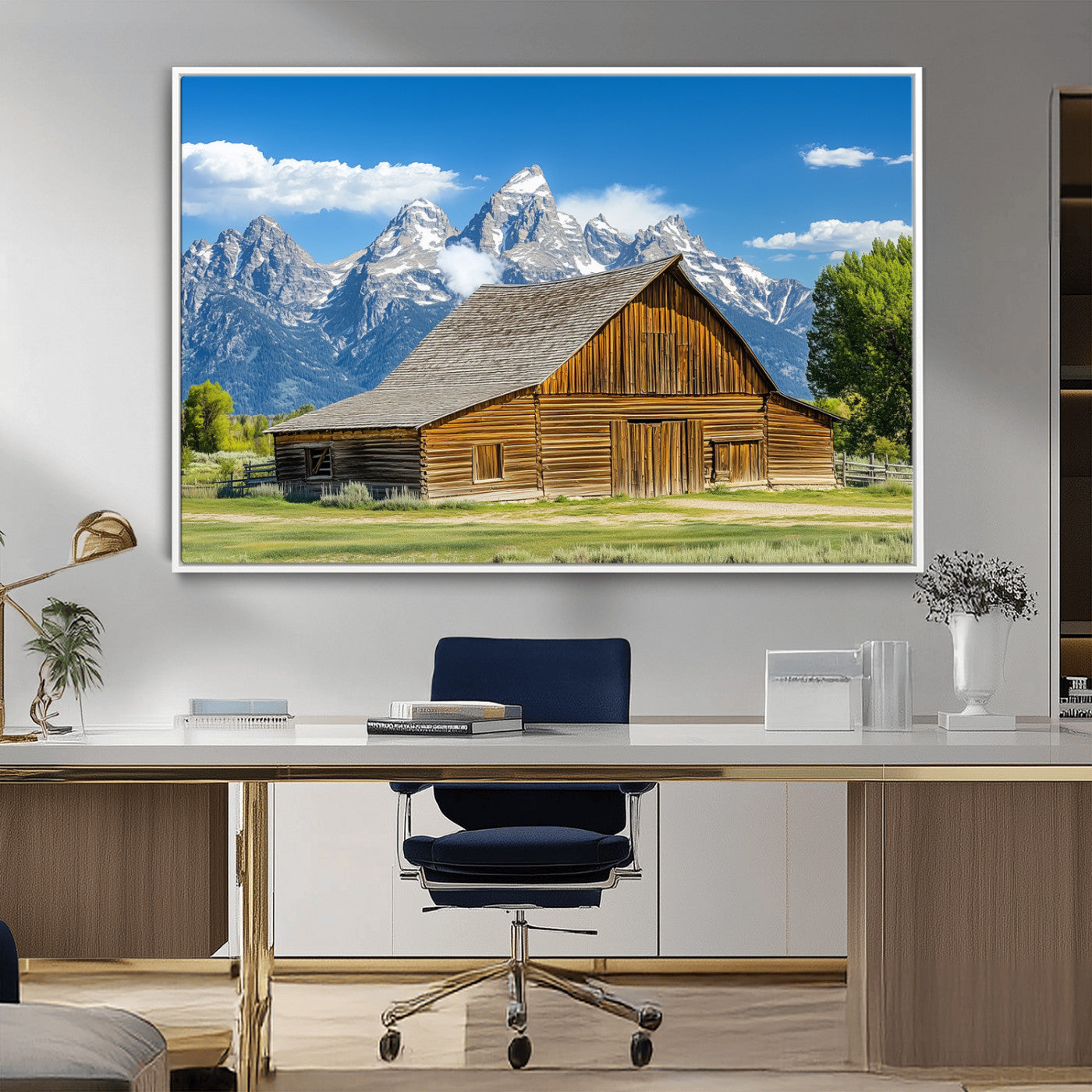 A rustic wooden barn sits in front of towering mountain peaks under a clear blue sky, perfect for farmhouse or cabin style interiors.