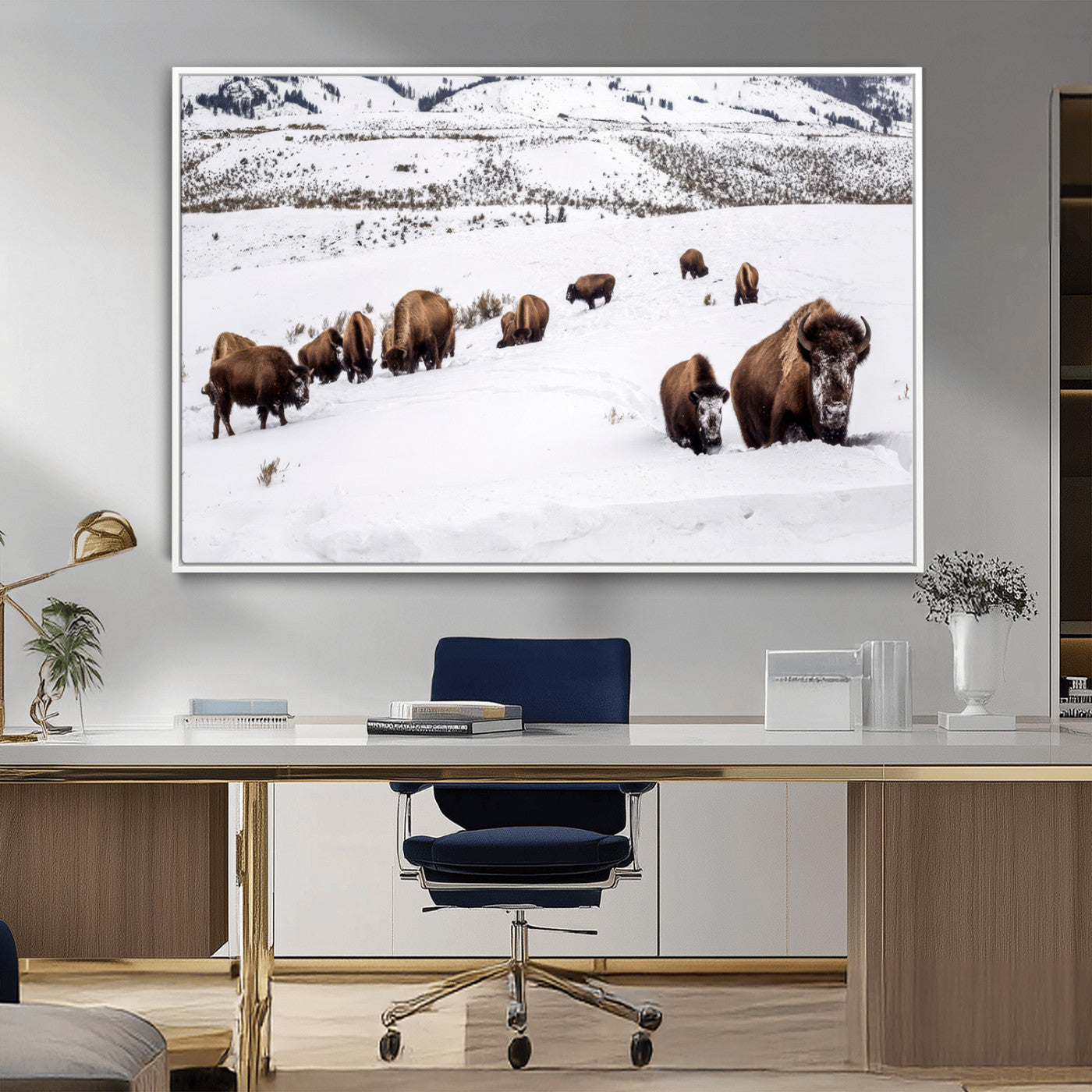 A herd of bison walking through deep snow in a mountain valley, perfect for rustic, cabin or western-themed wall decor.