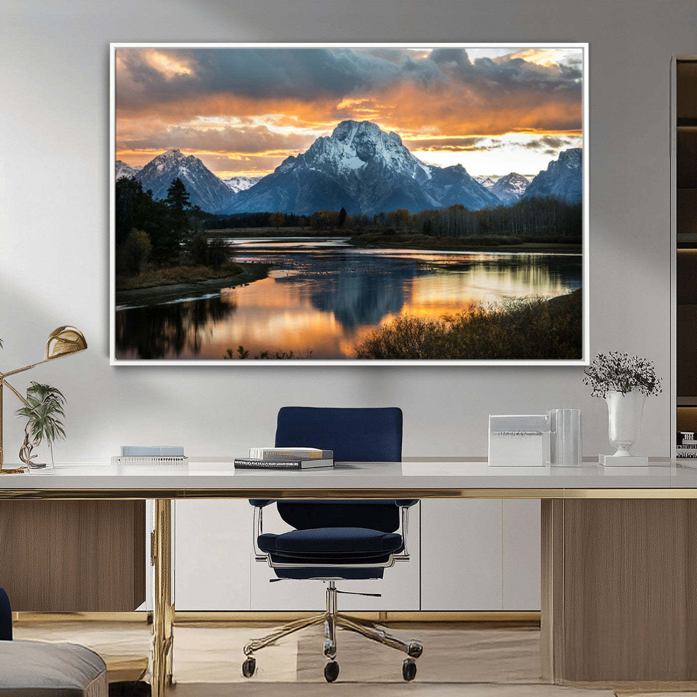 Snow-capped mountains reflecting in a calm lake at sunset, with a dramatic golden sky creating a breathtaking wilderness scene.