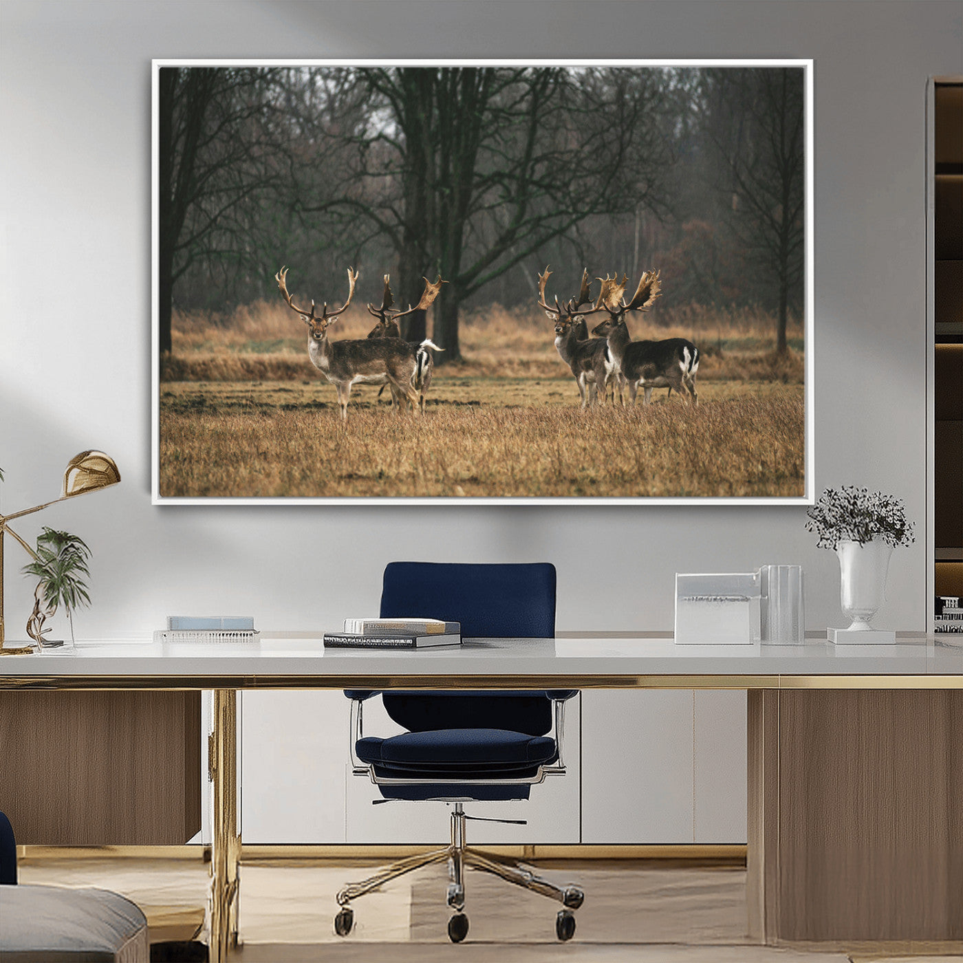 A group of majestic deer standing in a golden field with bare trees in the background, creating a peaceful woodland scene.