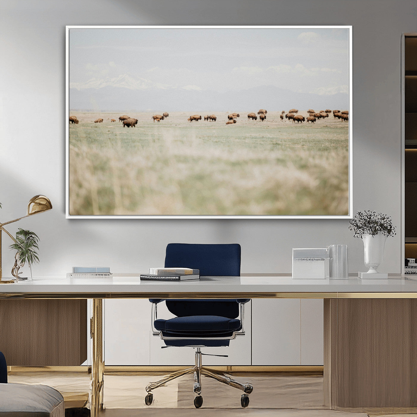 A herd of bison grazing in an open prairie with distant mountains under a soft sky, creating a serene and rustic Western landscape.
