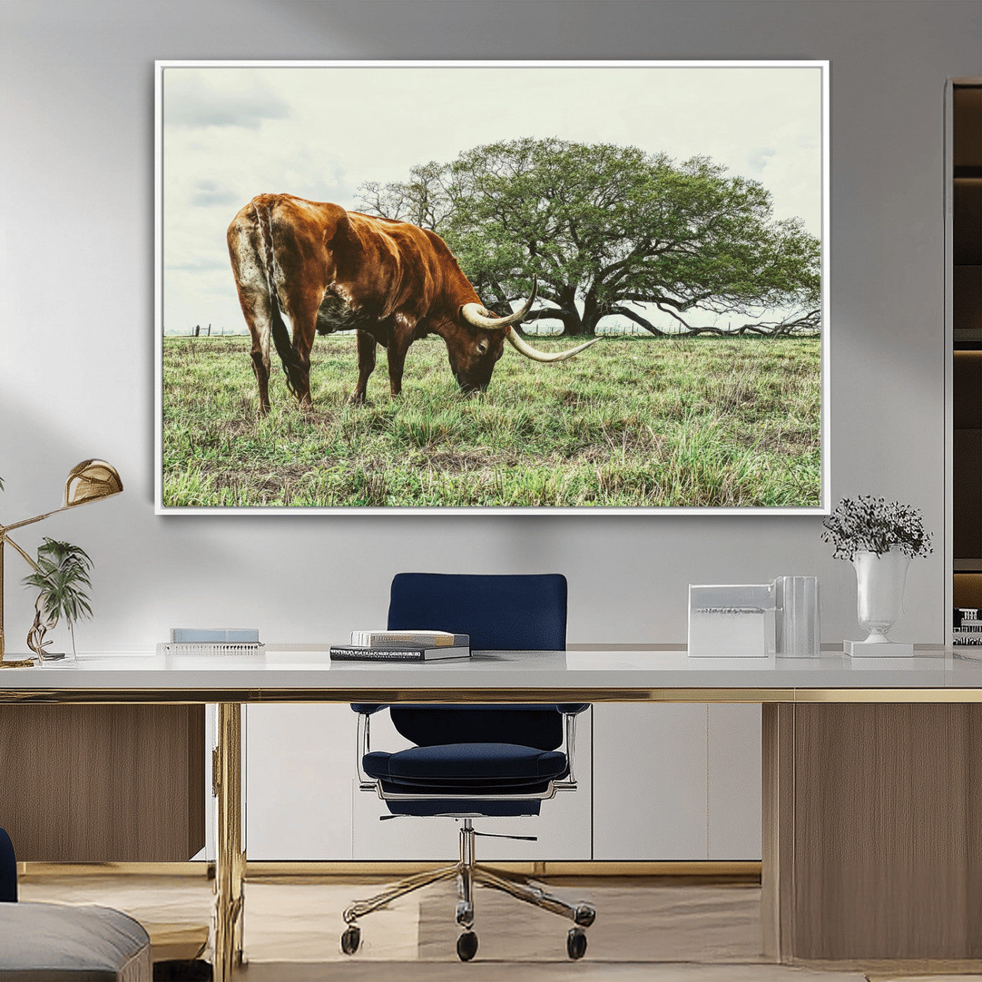 A Texas Longhorn grazing in a green pasture with a large tree in the background, evoking a rustic Western and farmhouse aesthetic.