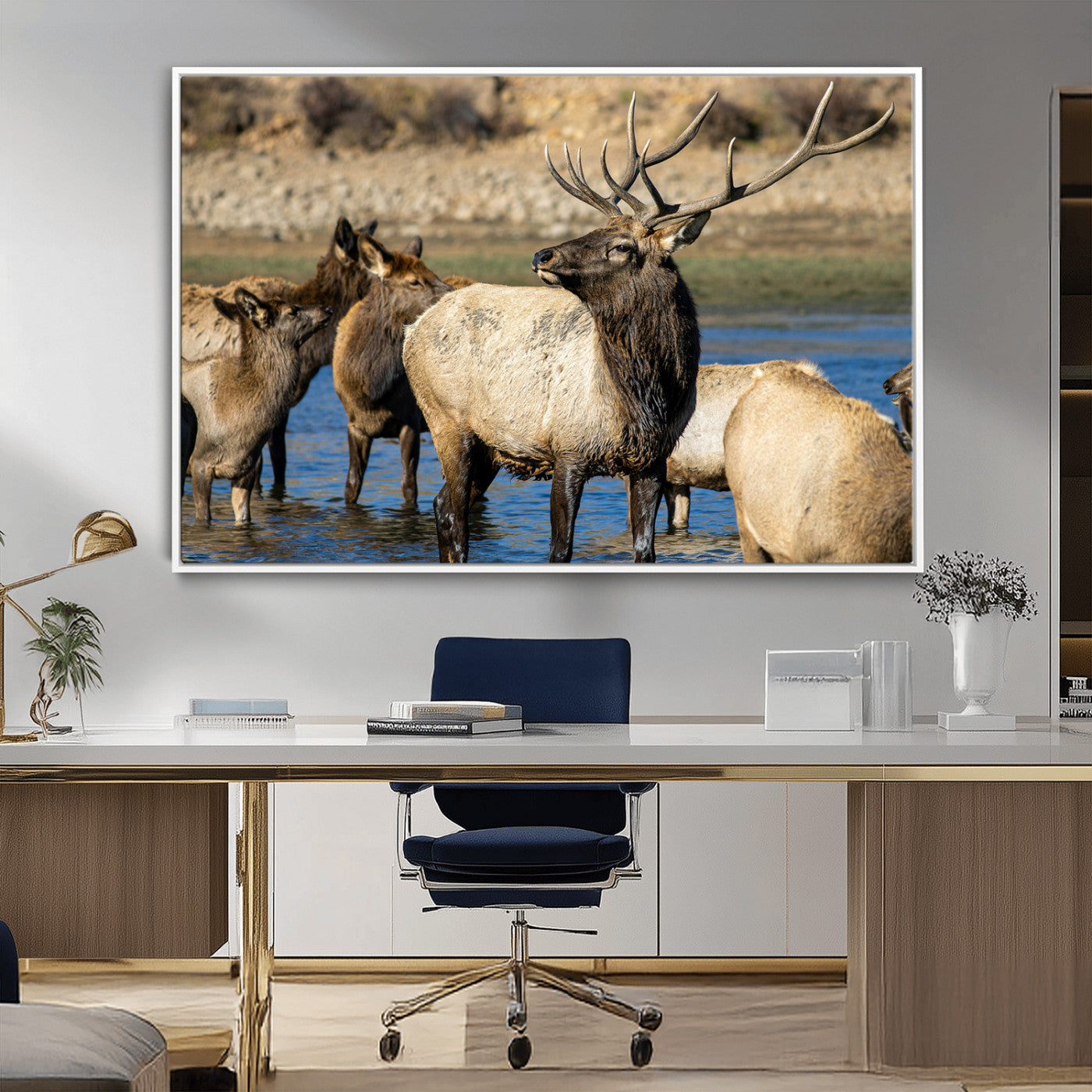 Group of elk standing in shallow water with dry rocky terrain in the background, showcasing wildlife in a natural setting for rustic decor.