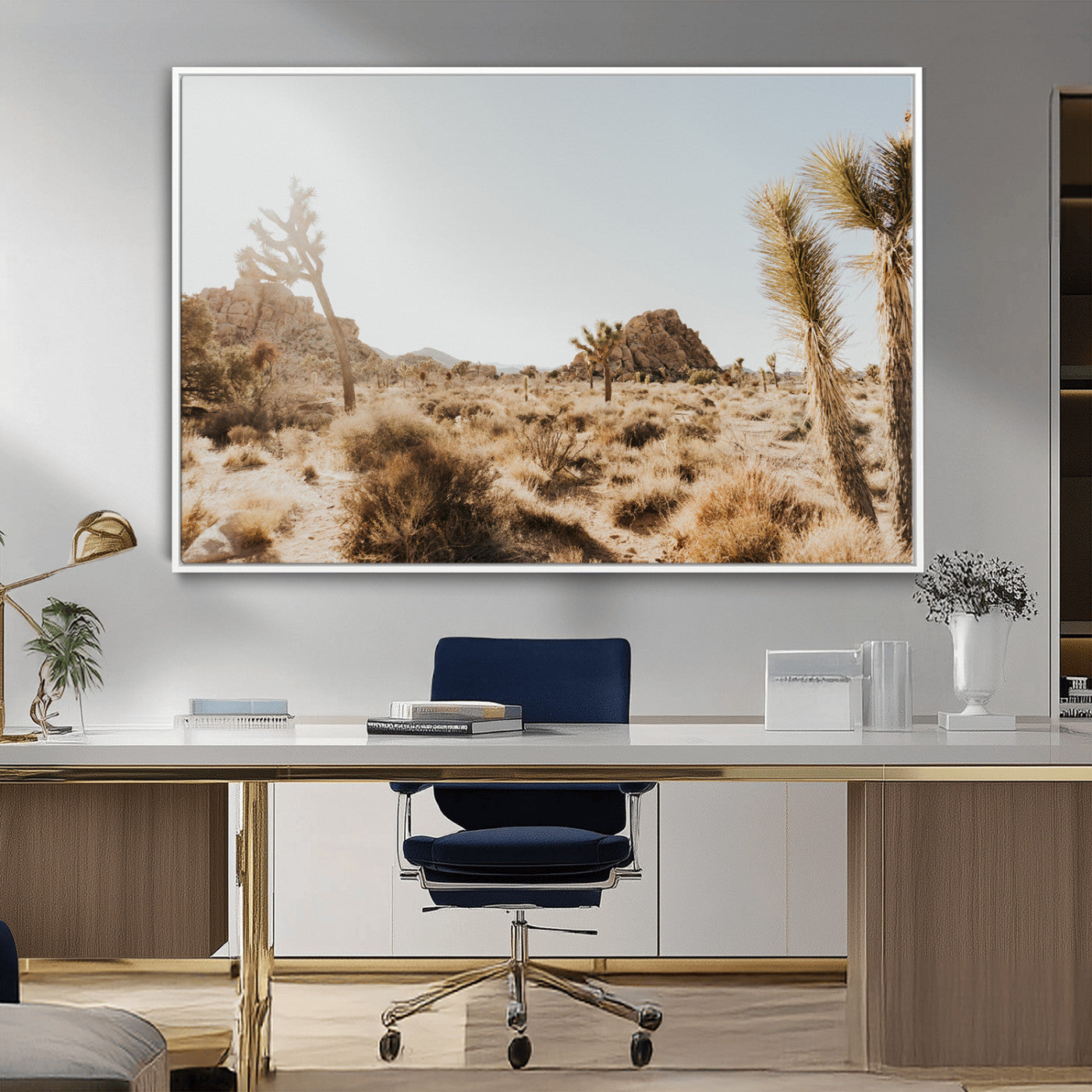 Sunlit desert landscape featuring Joshua trees, rocky formations, and dry bushes under a clear sky.