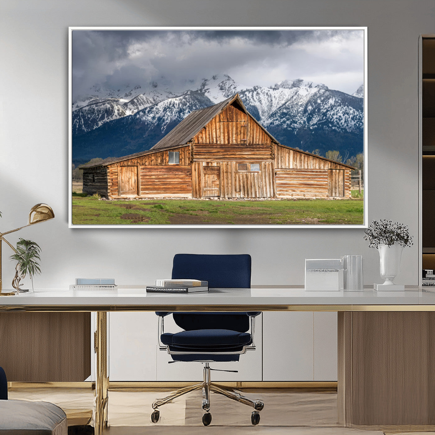 A stunning wall art canvas print featuring a rustic wooden barn set against a backdrop of snow-capped mountains under a dramatic cloudy sky, perfect for adding a touch of rural charm to any space.