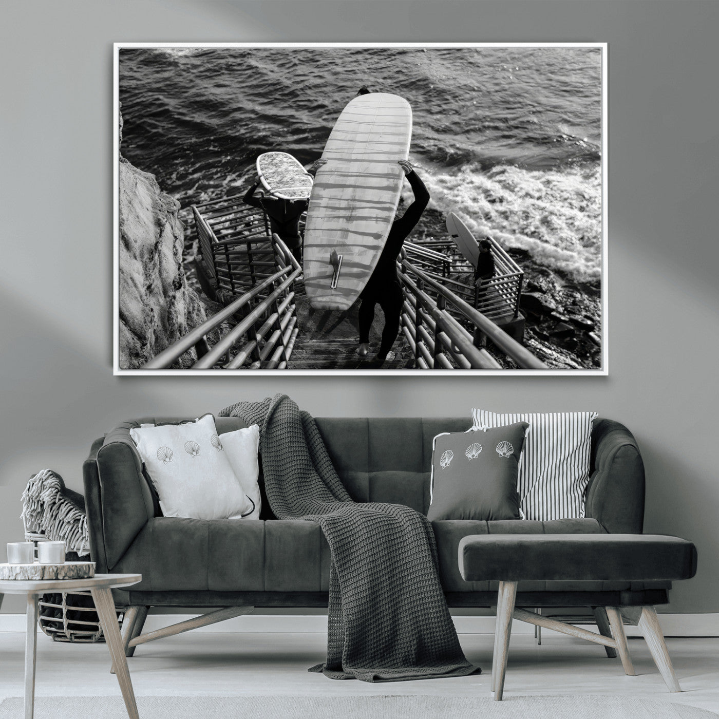 Black and white photo of surfers carrying boards down a rugged cliffside stairway, capturing a bold and adventurous coastal scene.