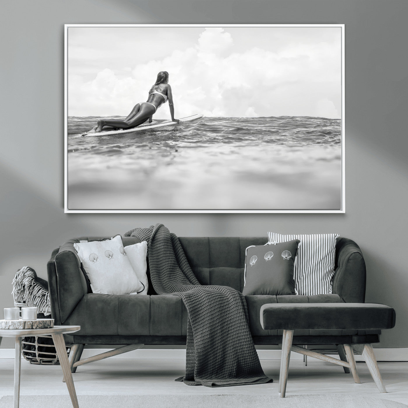 A black and white ocean scene featuring a surfer girl waiting on her board, gazing at the horizon, capturing a tranquil and adventurous coastal moment.