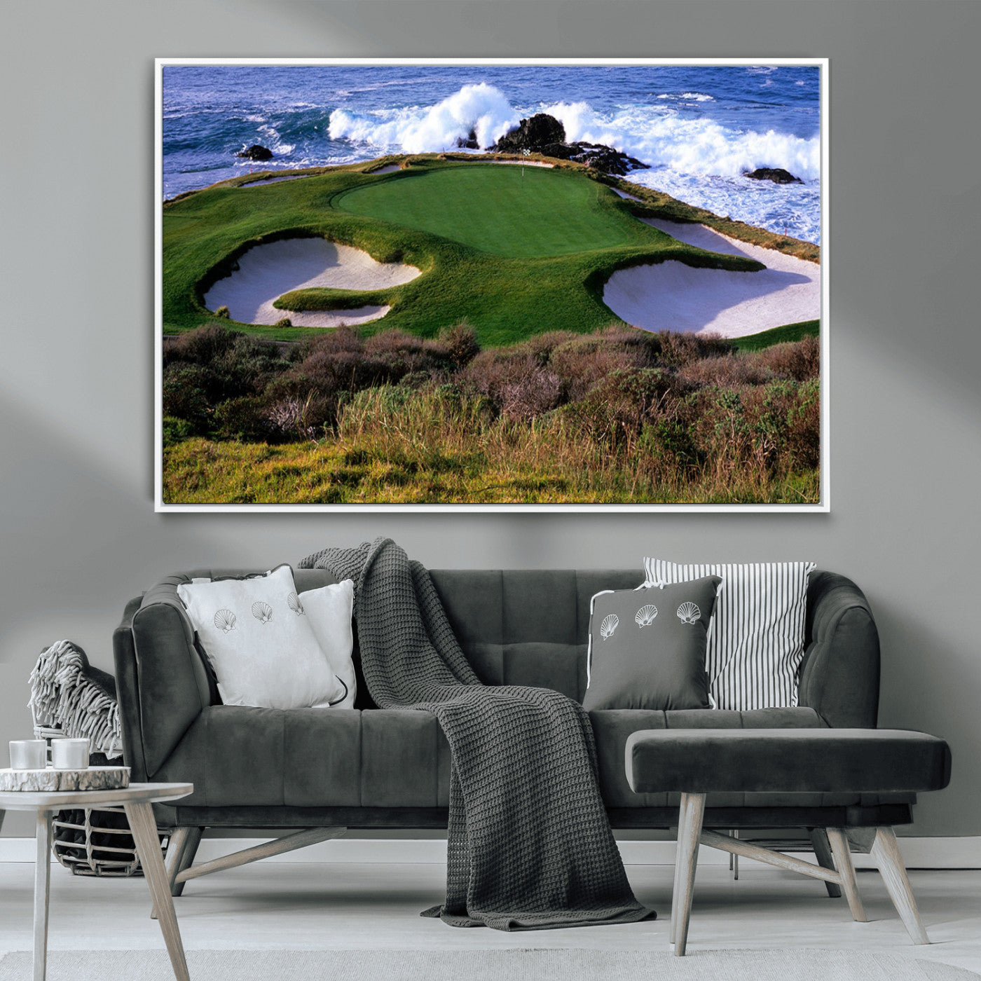 A scenic golf course located by the ocean, featuring a well-manicured green surrounded by sand traps and powerful ocean waves crashing on the shore.
