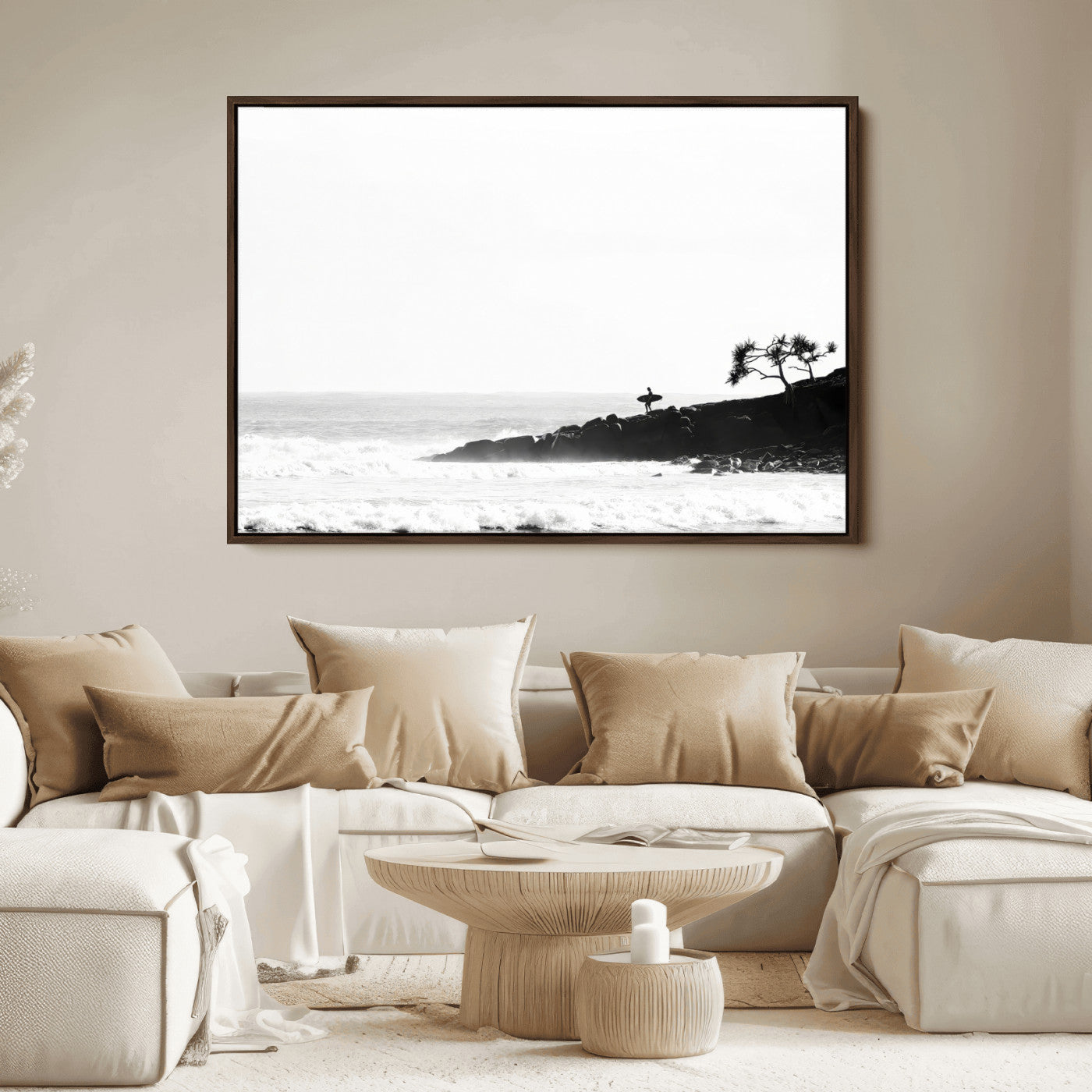 Black and white photo of a surfer standing on rocky cliffs, gazing at the waves, embodying the spirit of adventure and solitude.