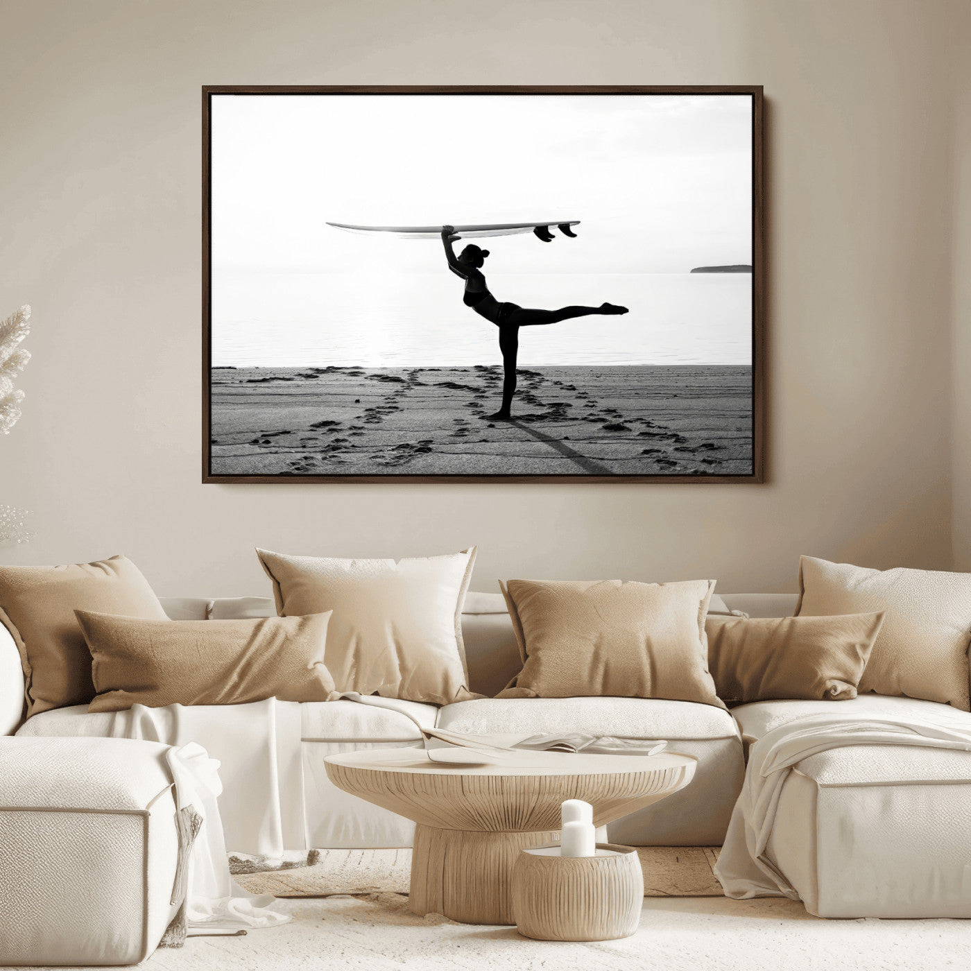 A woman balances a surfboard on her head while striking a yoga pose on the beach, silhouetted against a calm ocean horizon.