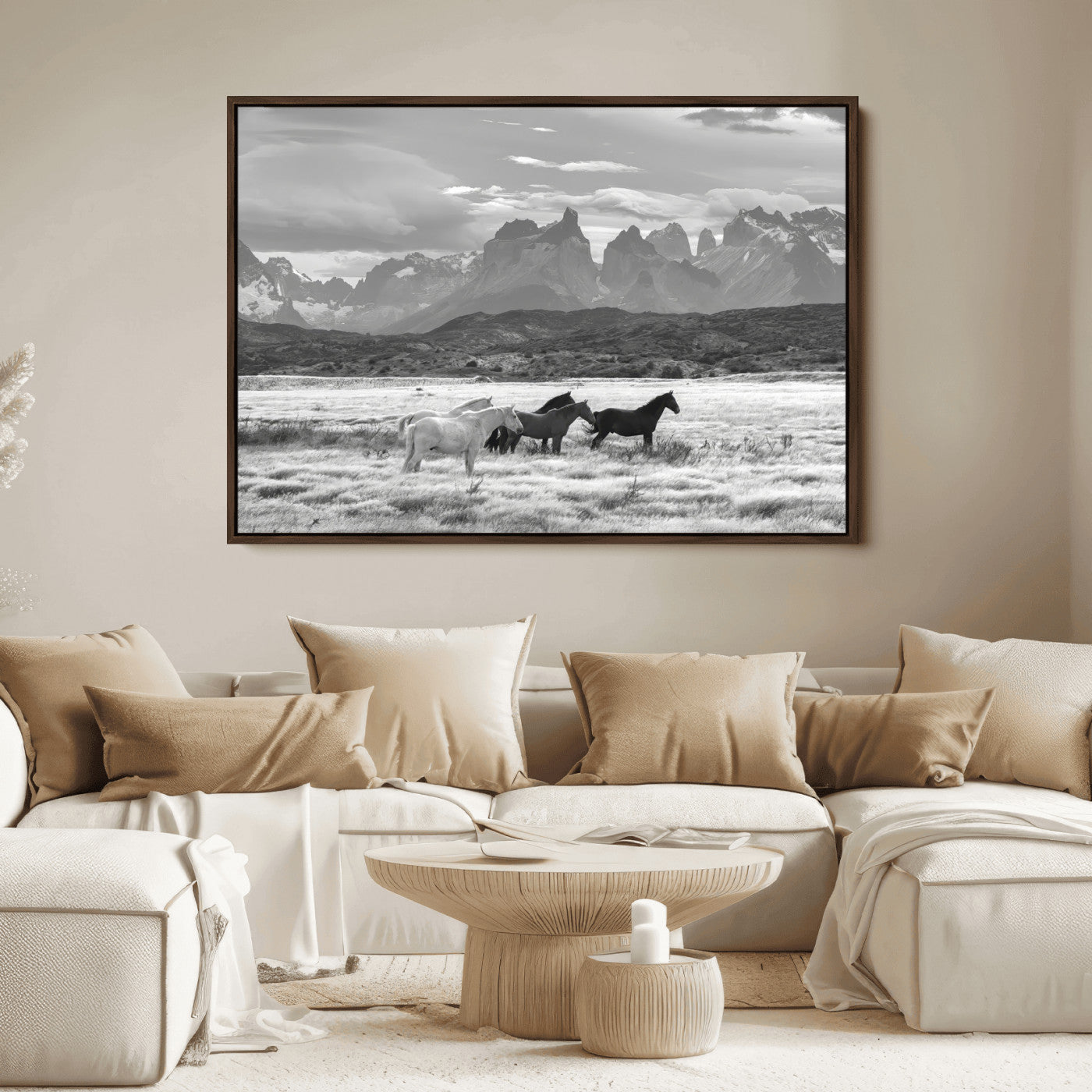 A black and white landscape of wild horses grazing in a vast grassland with towering mountains in the background, creating a moody and rustic western aesthetic.