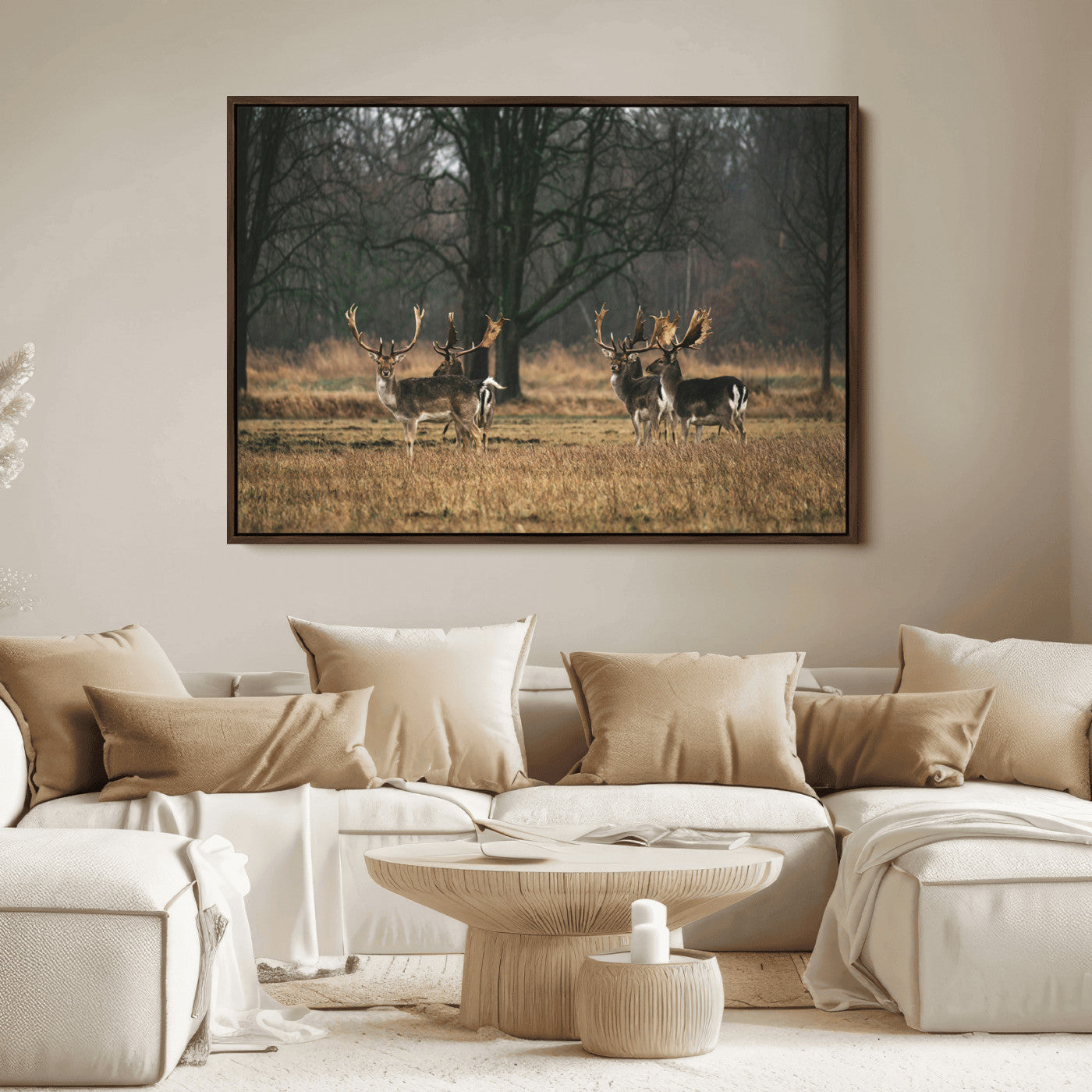 A group of majestic deer standing in a golden field with bare trees in the background, creating a peaceful woodland scene.