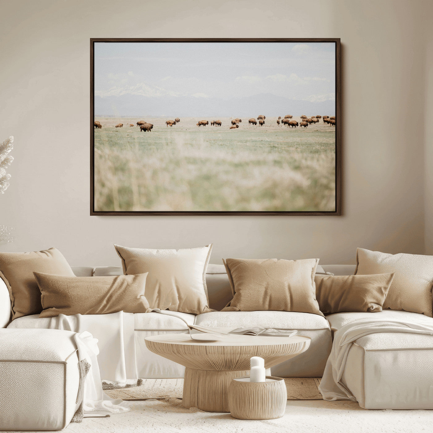 A herd of bison grazing in an open prairie with distant mountains under a soft sky, creating a serene and rustic Western landscape.