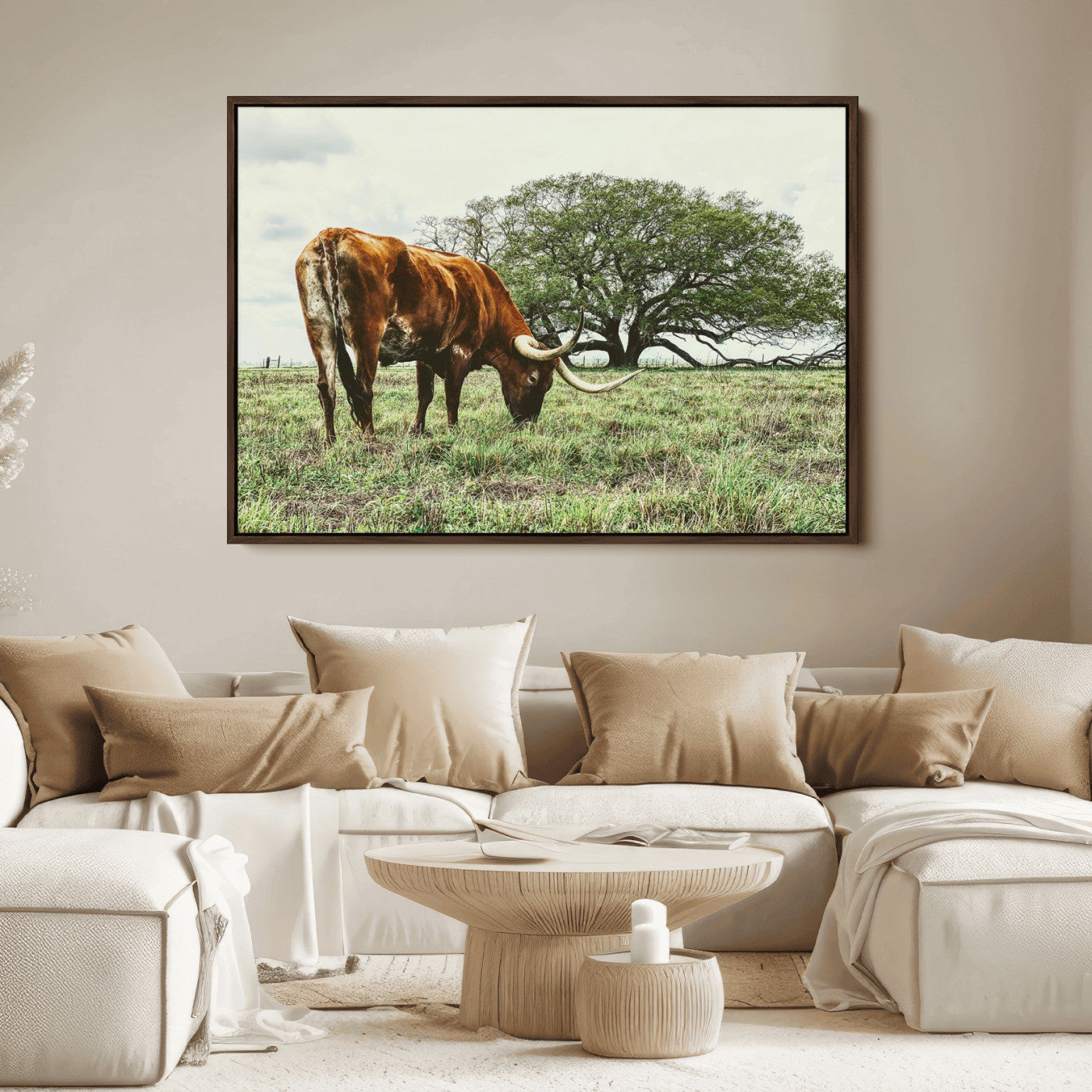 A Texas Longhorn grazing in a green pasture with a large tree in the background, evoking a rustic Western and farmhouse aesthetic.