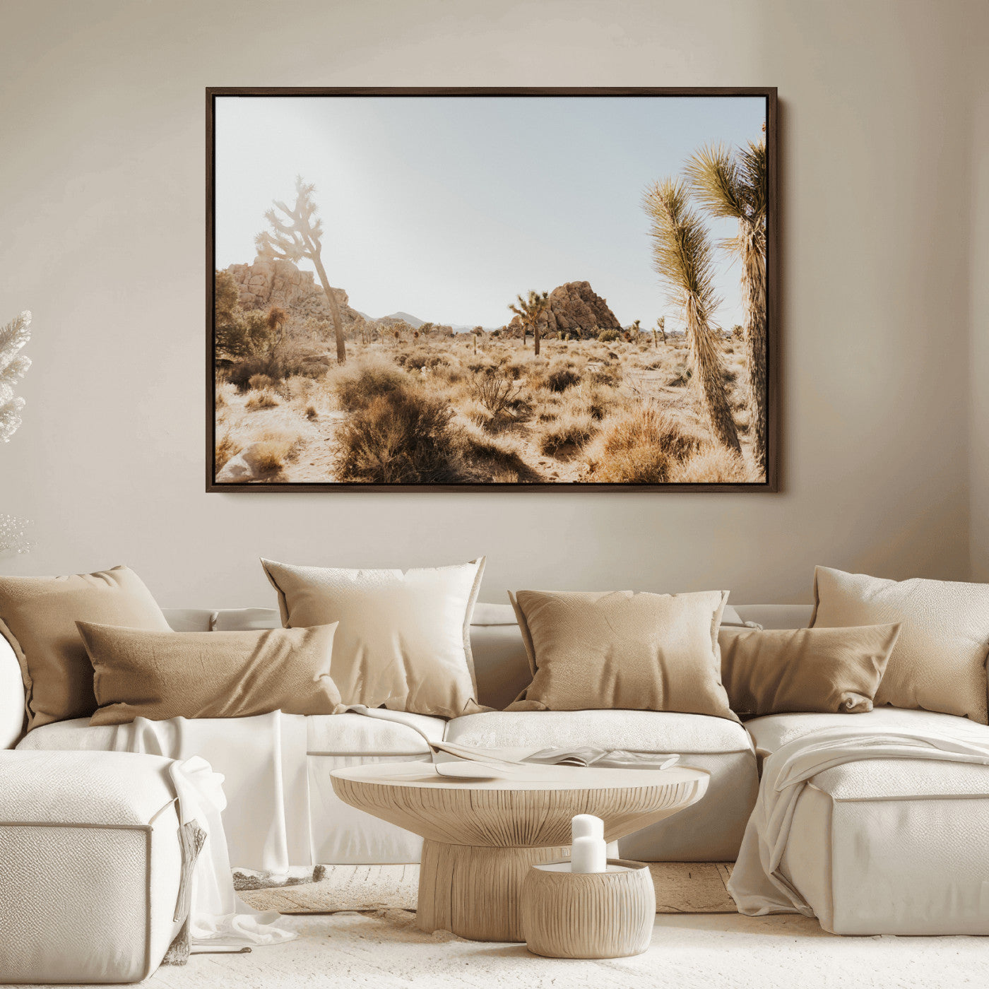 Sunlit desert landscape featuring Joshua trees, rocky formations, and dry bushes under a clear sky.