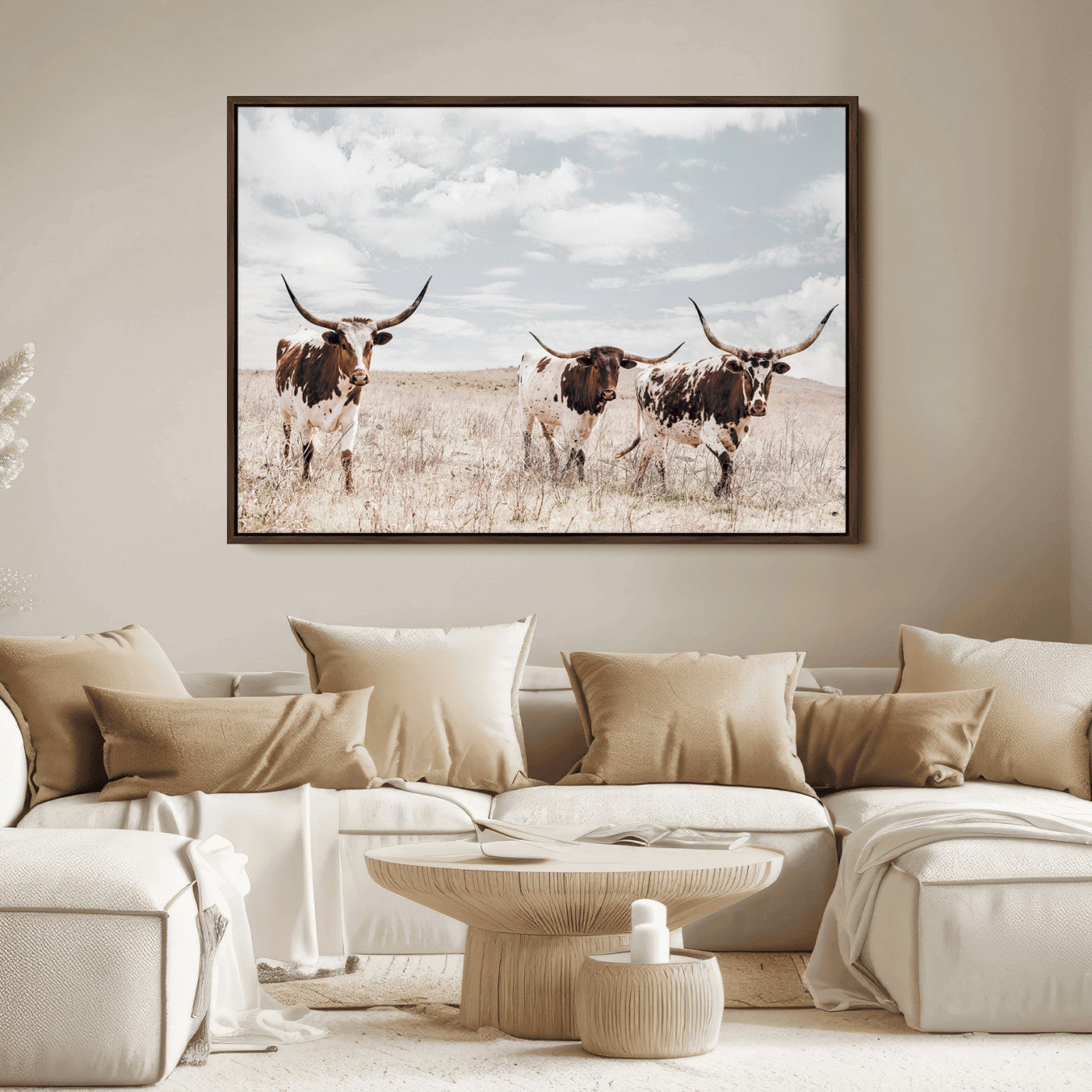 Three Texas Longhorn cattle walking through a dry grassy field under a partly cloudy sky.