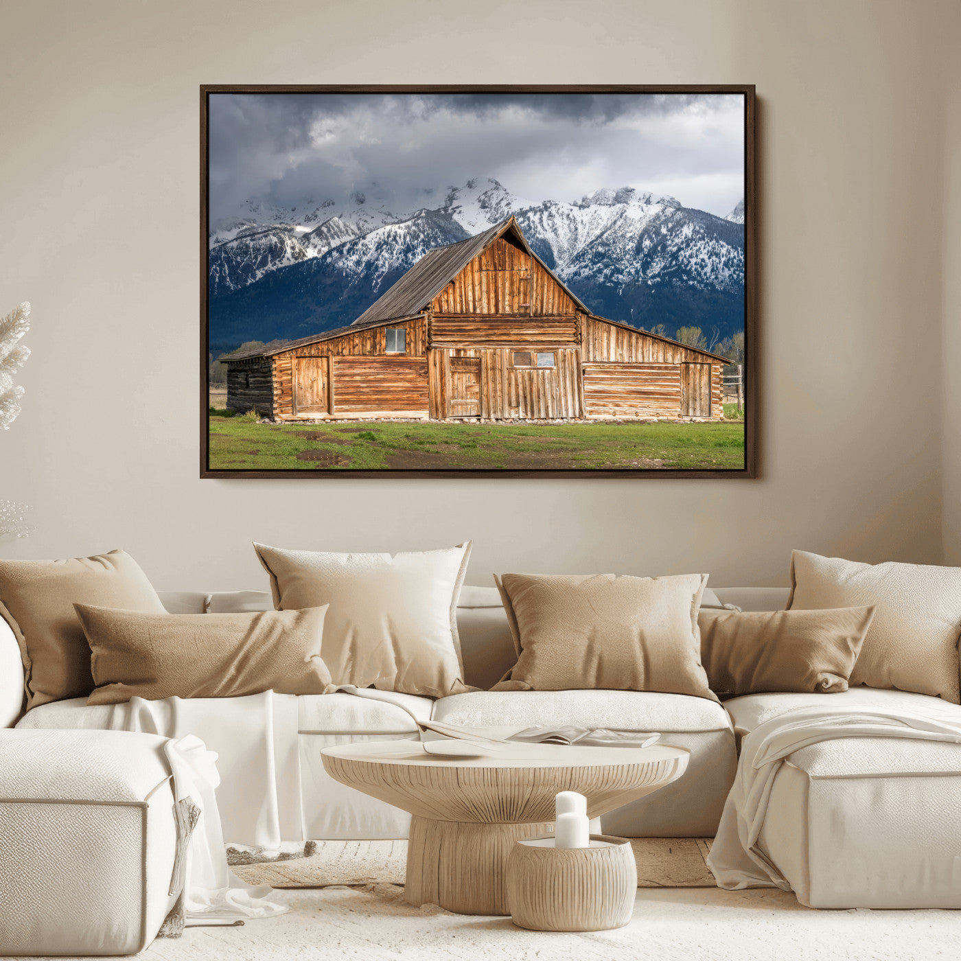 A stunning wall art canvas print featuring a rustic wooden barn set against a backdrop of snow-capped mountains under a dramatic cloudy sky, perfect for adding a touch of rural charm to any space.