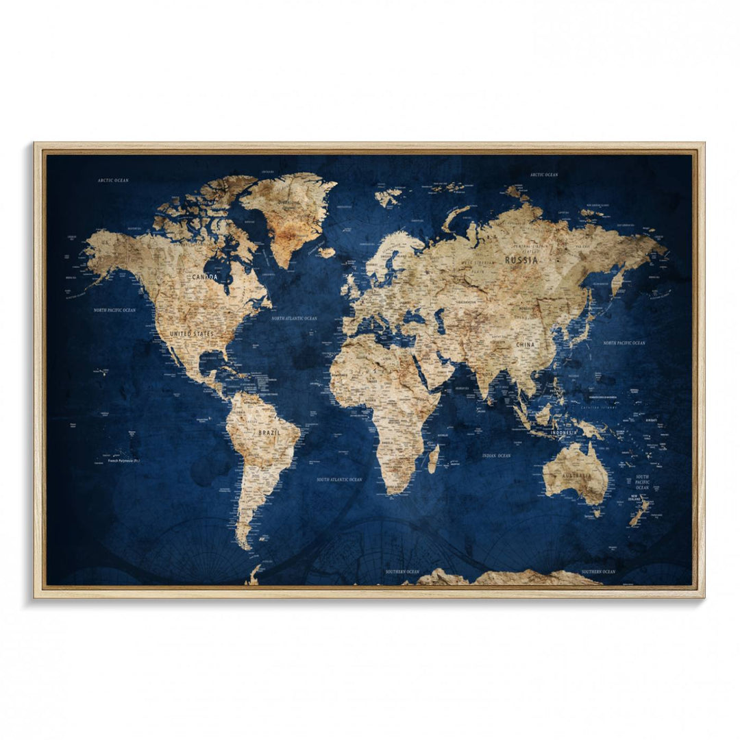 A large framed world map canvas print features beige landmasses set against a grunge-stained deep blue ocean background, creating an intriguing piece of wall art.