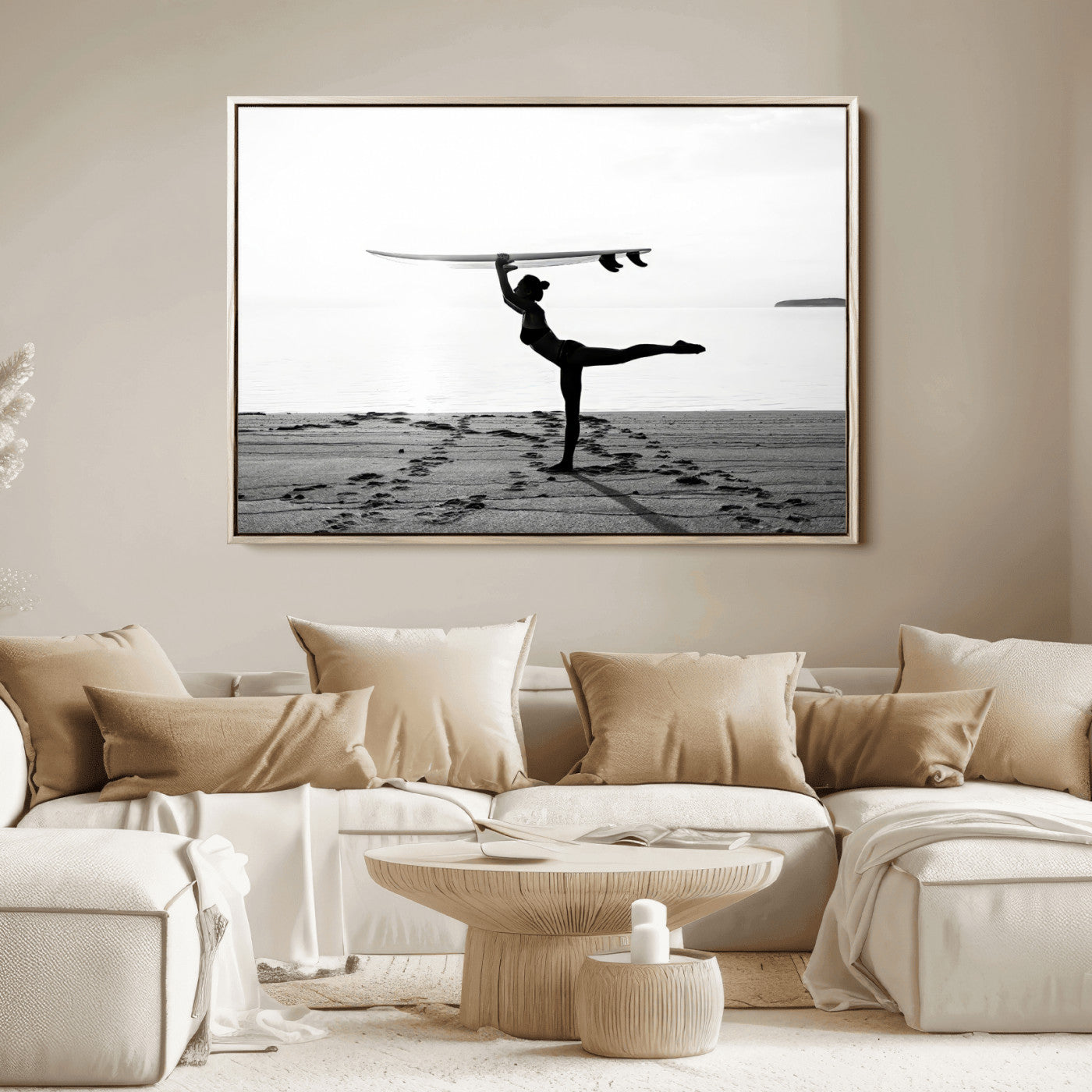 A woman balances a surfboard on her head while striking a yoga pose on the beach, silhouetted against a calm ocean horizon.