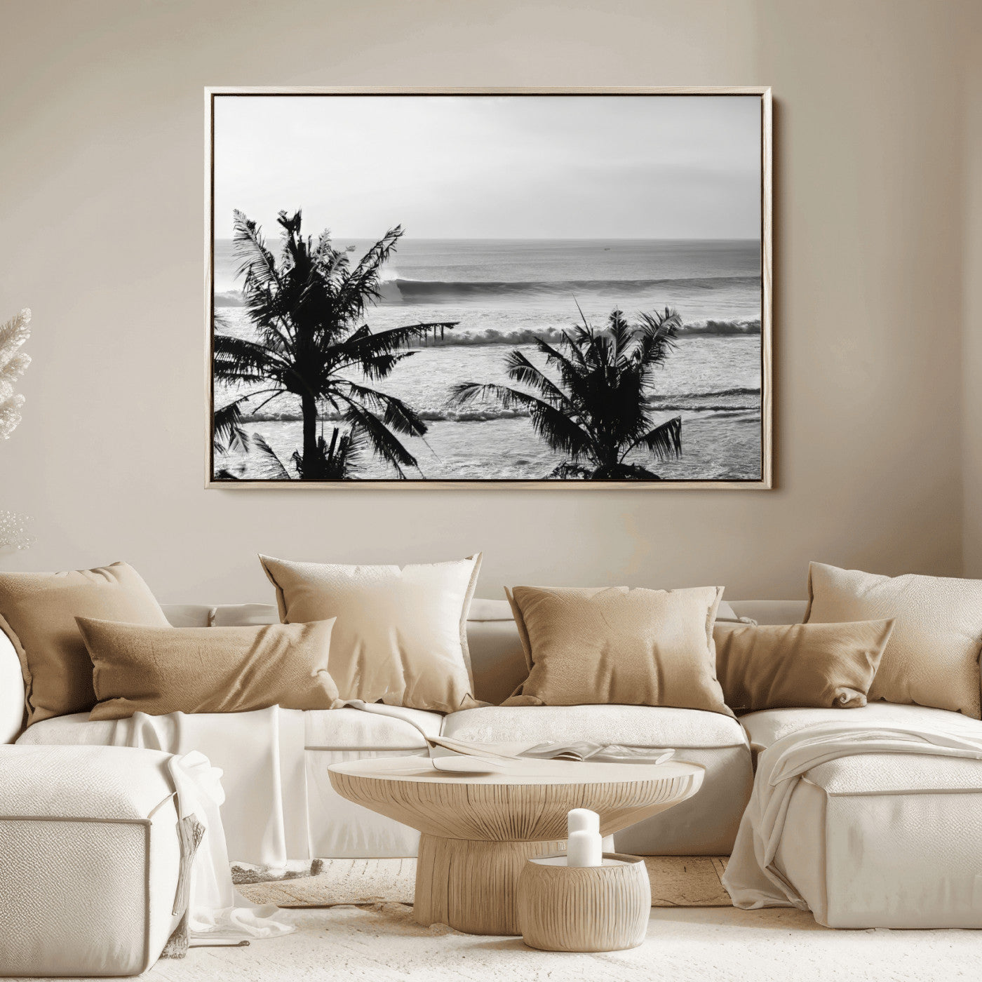 Black and white view of ocean waves crashing on a tropical coastline, framed by silhouetted palm trees under a vast, open sky.