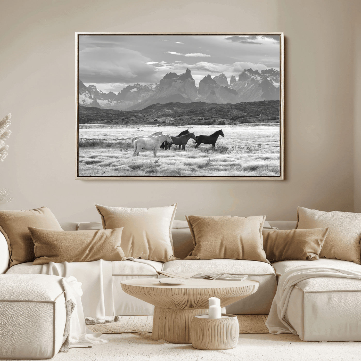 A black and white landscape of wild horses grazing in a vast grassland with towering mountains in the background, creating a moody and rustic western aesthetic.