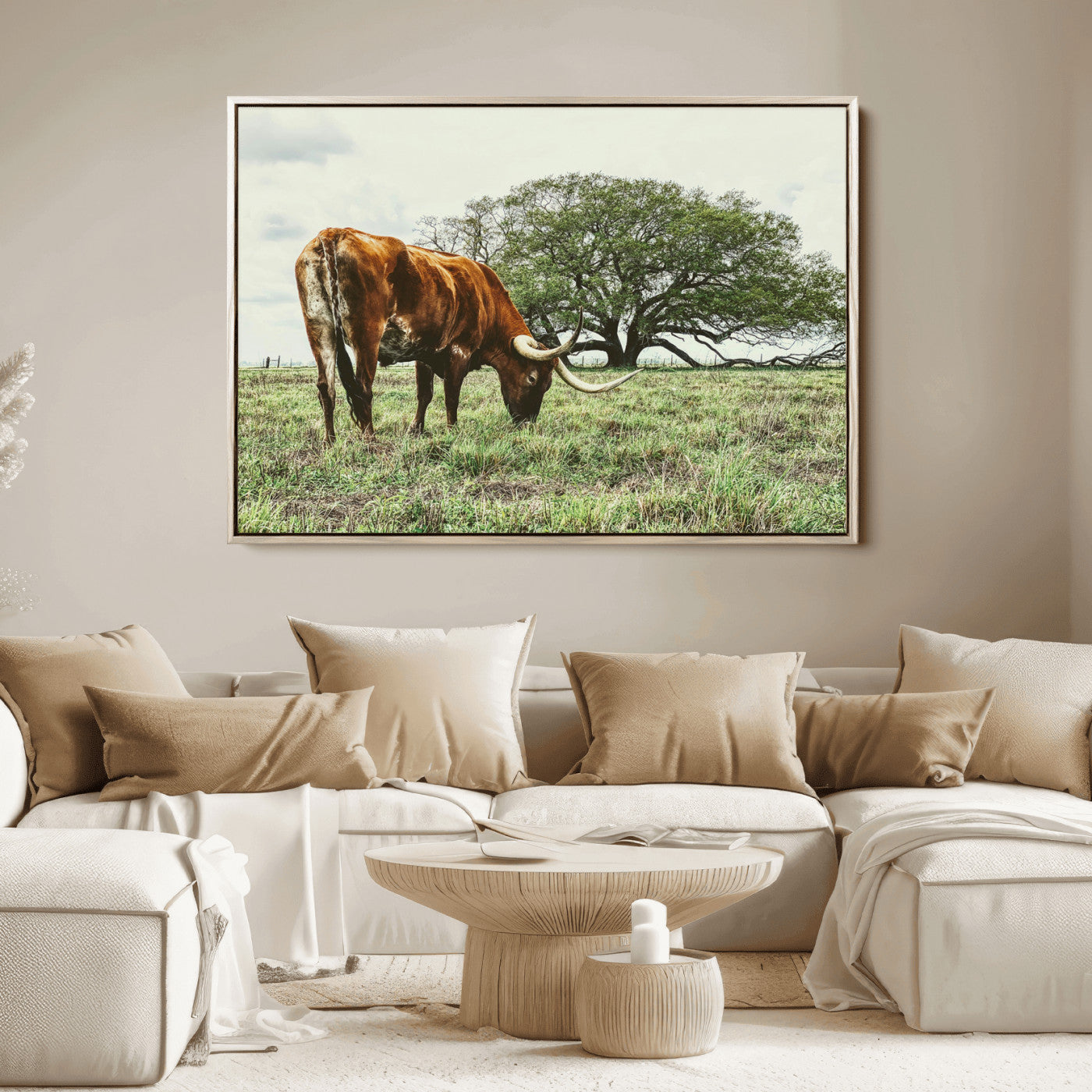 A Texas Longhorn grazing in a green pasture with a large tree in the background, evoking a rustic Western and farmhouse aesthetic.