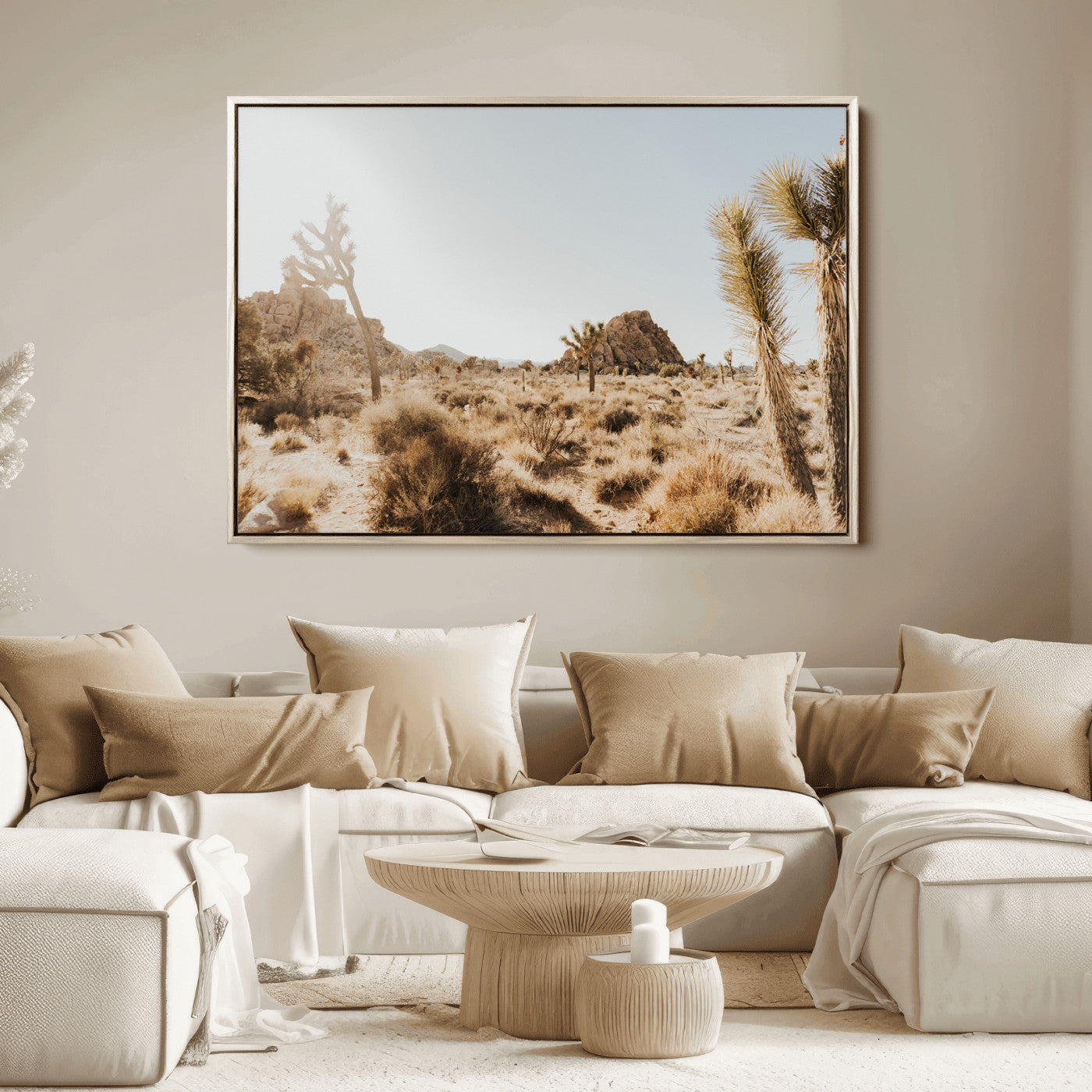 Sunlit desert landscape featuring Joshua trees, rocky formations, and dry bushes under a clear sky.