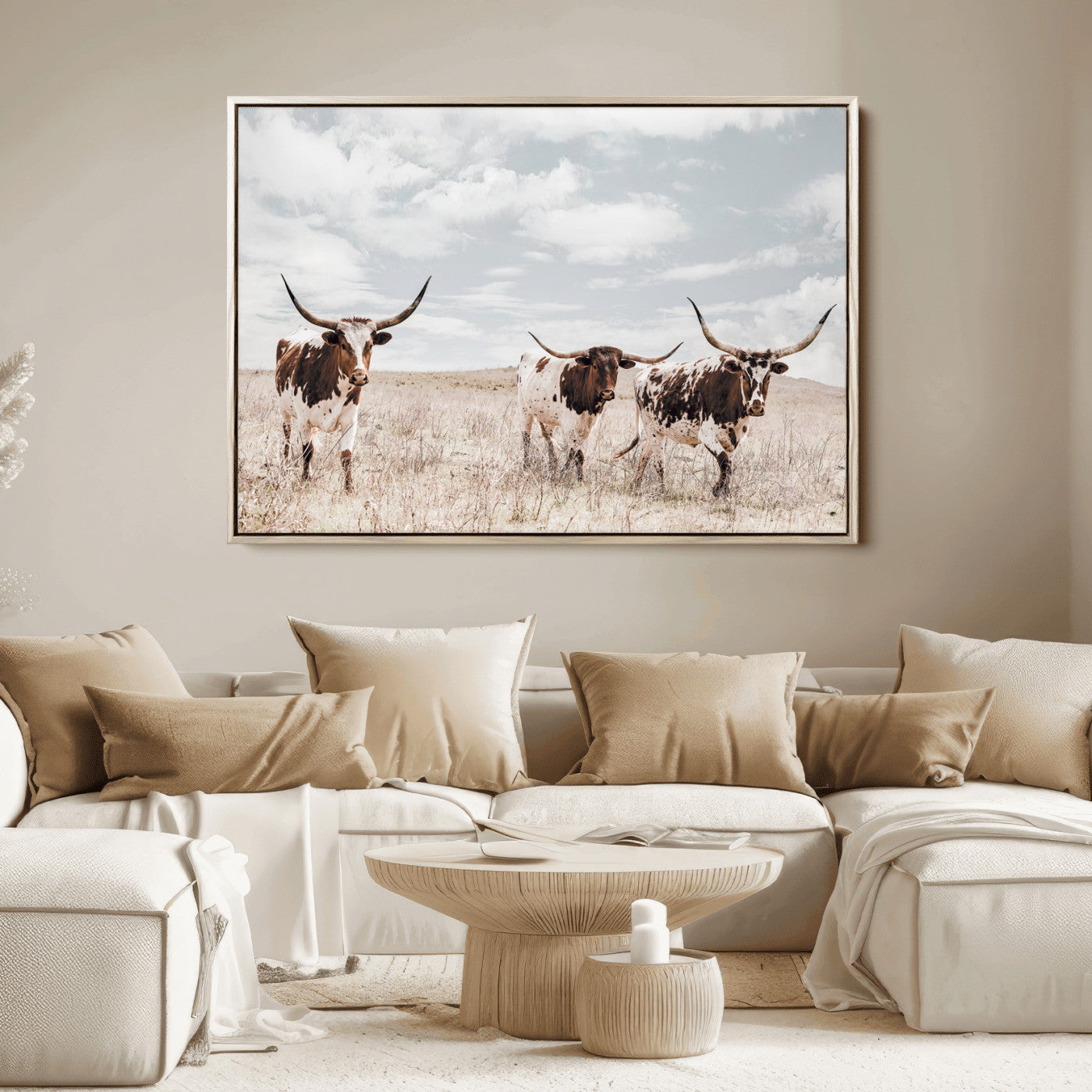 Three Texas Longhorn cattle walking through a dry grassy field under a partly cloudy sky.