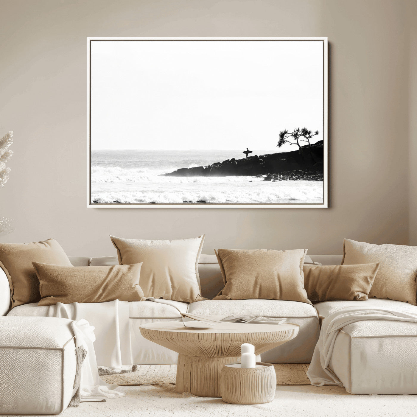 Black and white photo of a surfer standing on rocky cliffs, gazing at the waves, embodying the spirit of adventure and solitude.