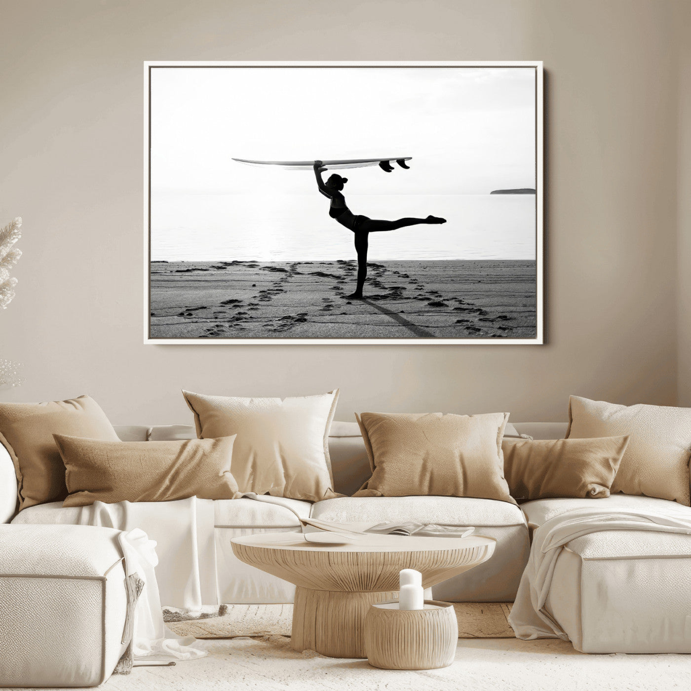 A woman balances a surfboard on her head while striking a yoga pose on the beach, silhouetted against a calm ocean horizon.
