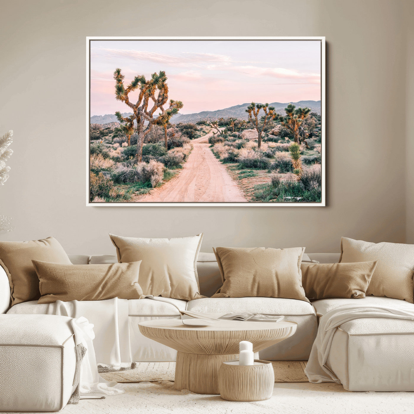 A dusty road winding through Joshua Tree National Park, framed by iconic twisted trees and warm desert tones under a soft pastel sky.