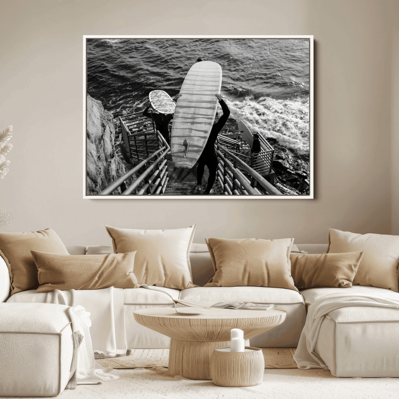 Black and white photo of surfers carrying boards down a rugged cliffside stairway, capturing a bold and adventurous coastal scene.