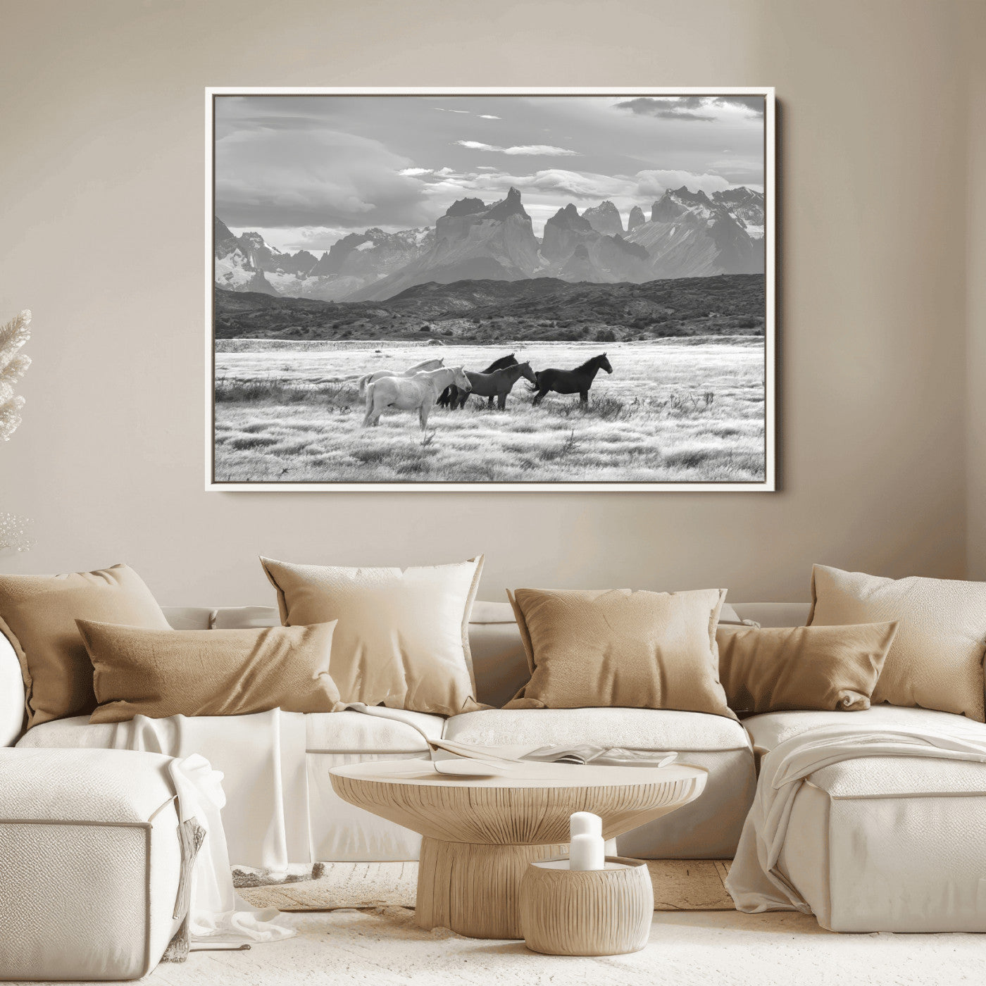 A black and white landscape of wild horses grazing in a vast grassland with towering mountains in the background, creating a moody and rustic western aesthetic.