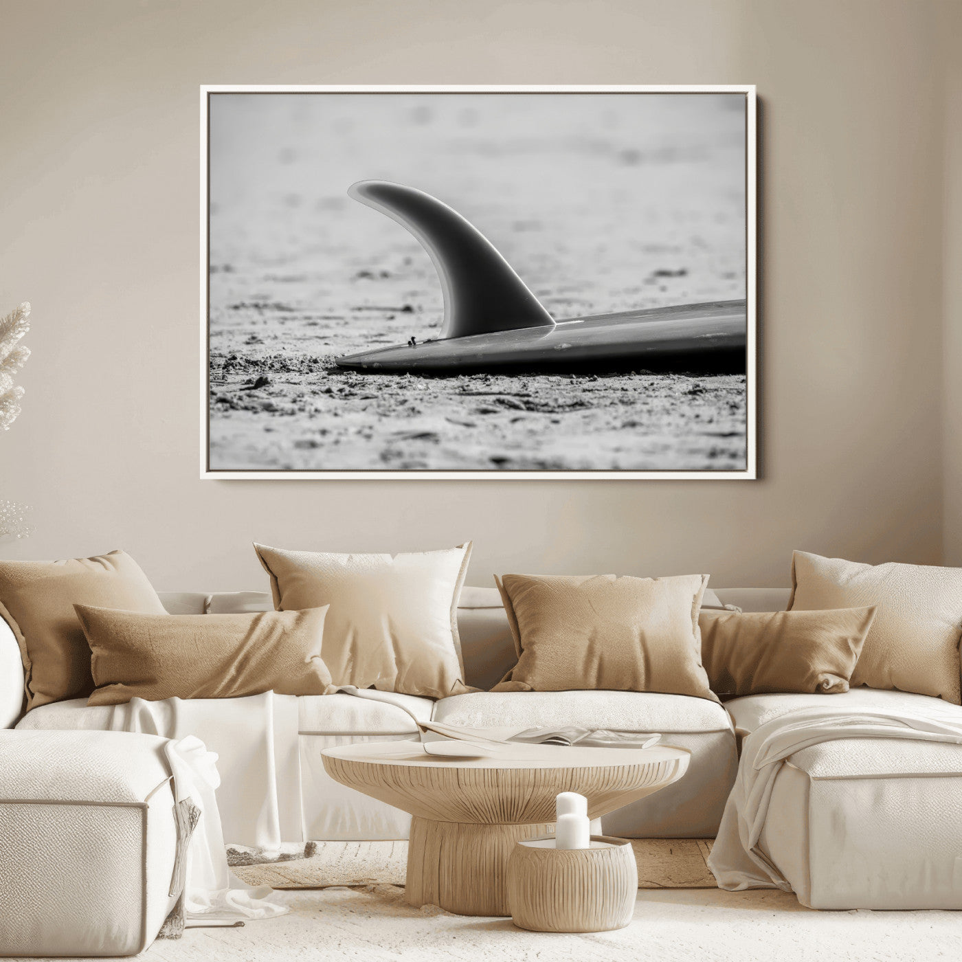 A black and white close-up of a surfboard fin resting on the sandy shore, highlighting minimalist beach aesthetics and classic surf culture.